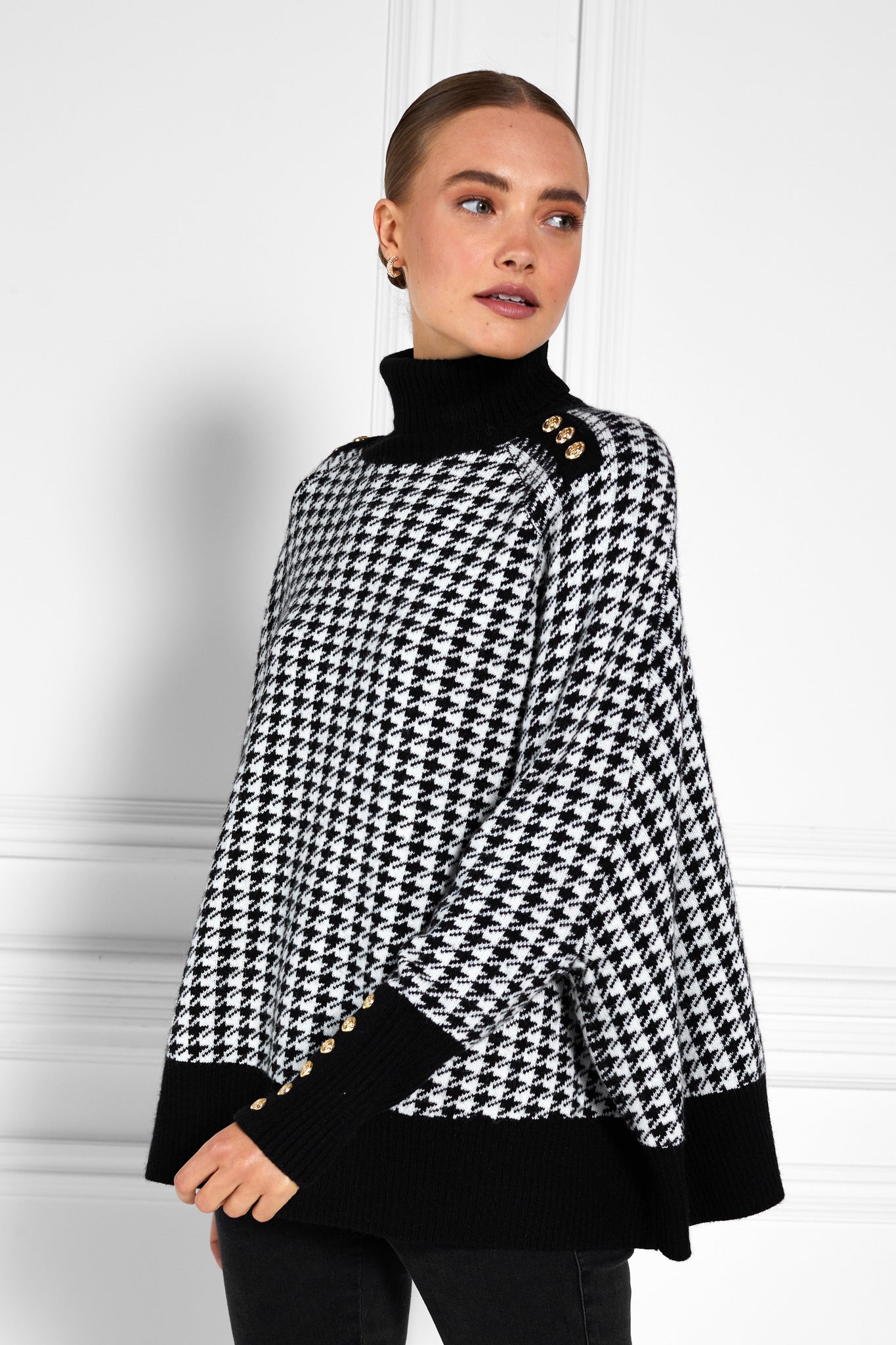 womens funnel neck batwing shaped cape in a white and black houndstooth knit with split side detail and contrast black neckline cuffs and hem