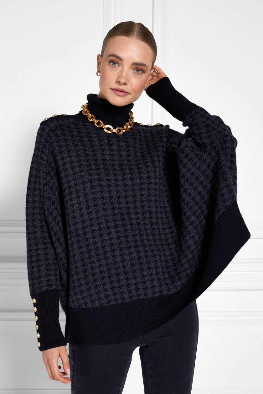 womens funnel neck batwing shaped cape in a grey and black houndstooth knit with split side detail and contrast black neckline cuffs and hem