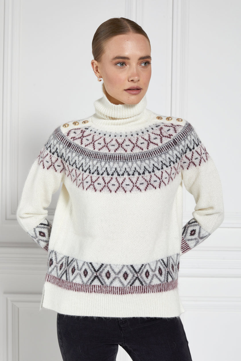 a classic cream roll neck jumper with fairisle knit in red and grey around the shoulders waistline and cuffs and a split ribbed hem 