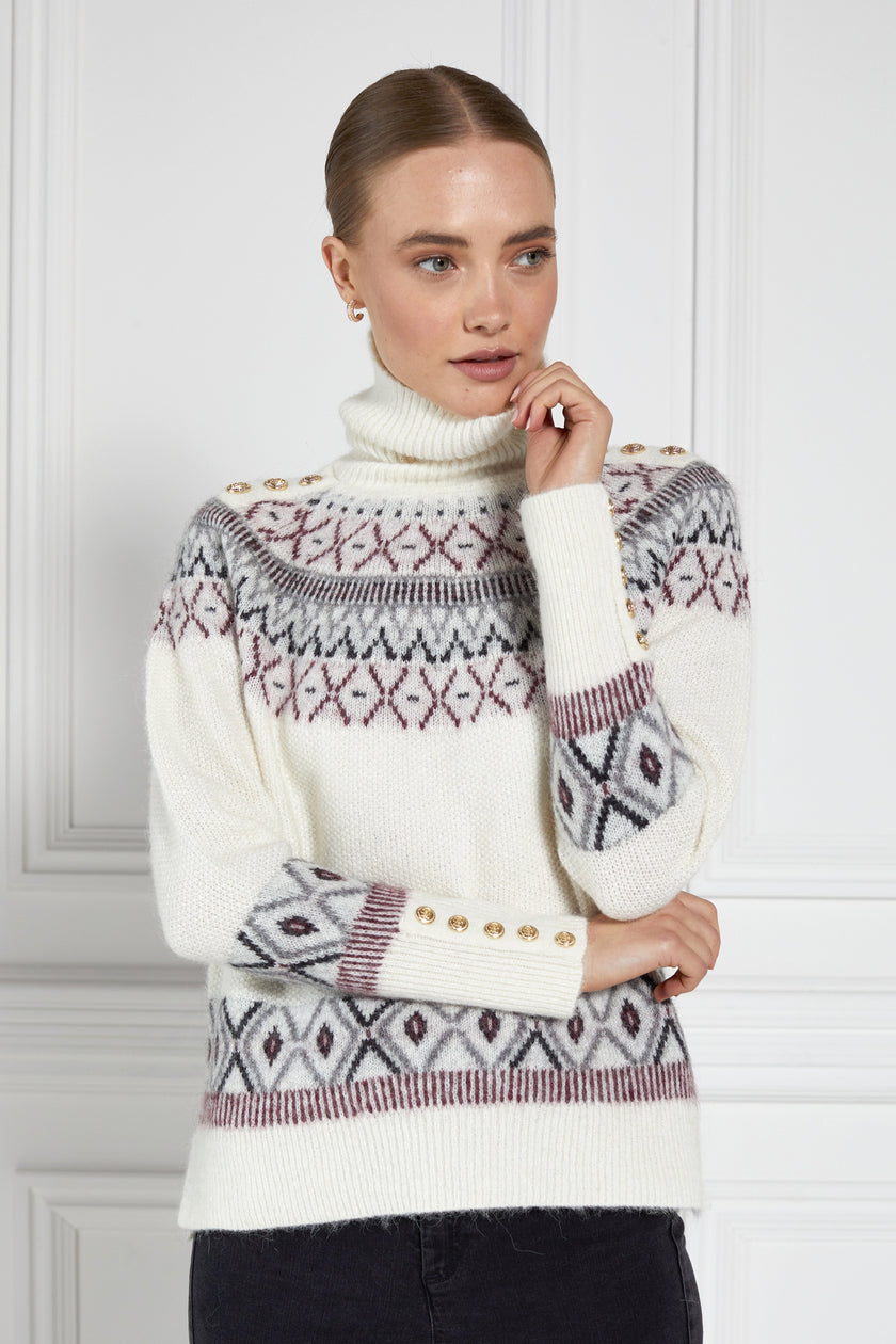 a classic cream roll neck jumper with fairisle knit in red and grey around the shoulders waistline and cuffs and a split ribbed hem 