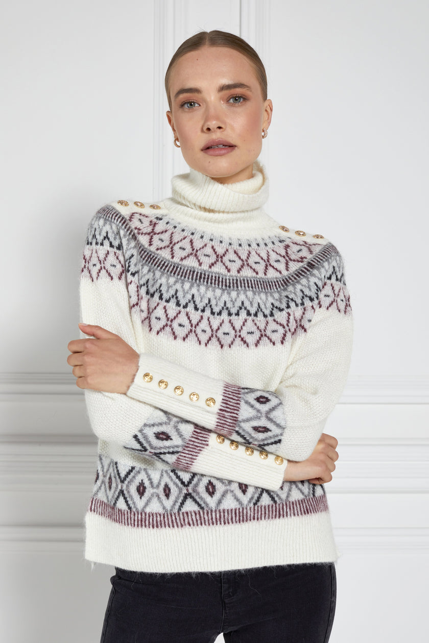 a classic cream roll neck jumper with fairisle knit in red and grey around the shoulders waistline and cuffs and a split ribbed hem 