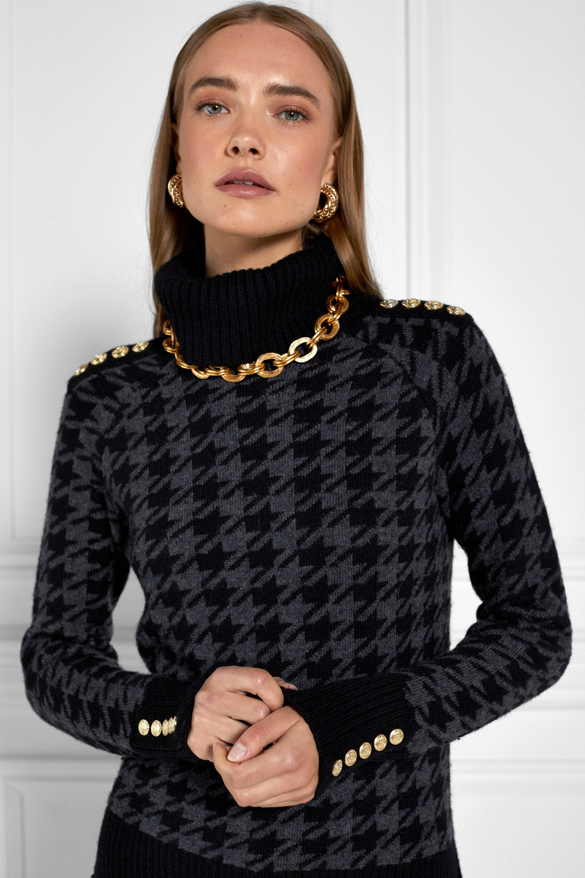 a classic black and grey houndstooth jumper with contrast black cuffs, roll neck and split ribbed hem with gold button detail on the cuffs and collar