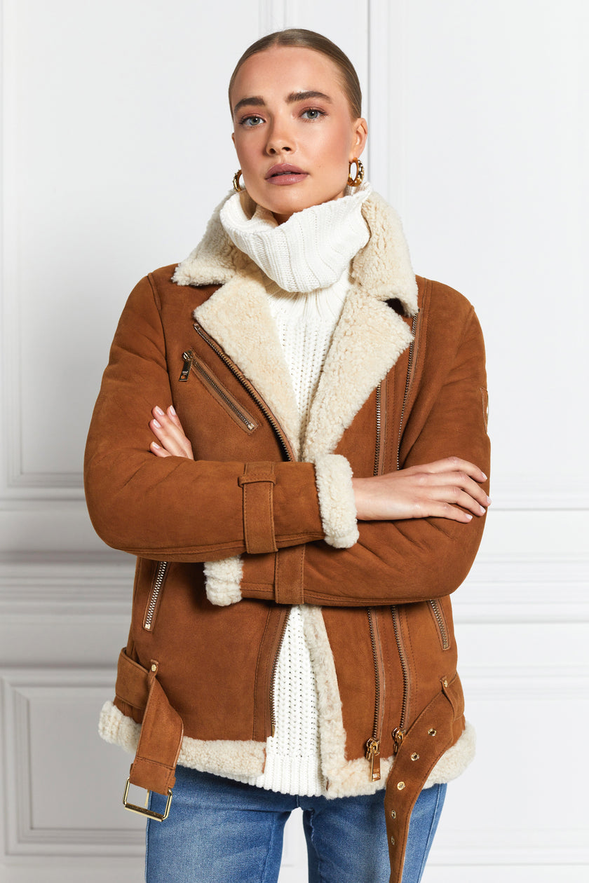 classic aviator jacket in tan leather with cream shearling inside that accents the cuffs hem and collar with belt detail on the hem and cuffs three pockets and angular zip fastening