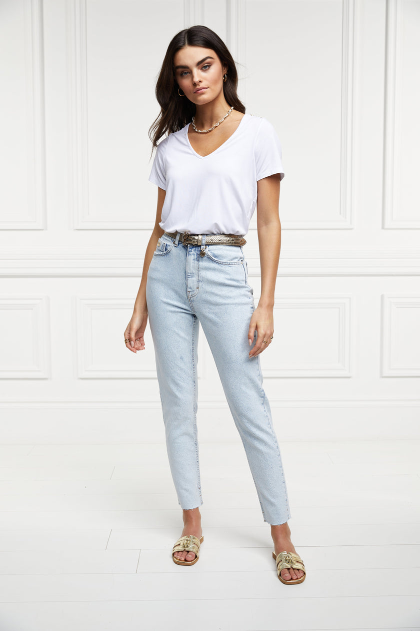 womens high rise light blue denim slim fit jean with raw hem and two open pockets on the front and back with gold stirrup charm to the belt loop