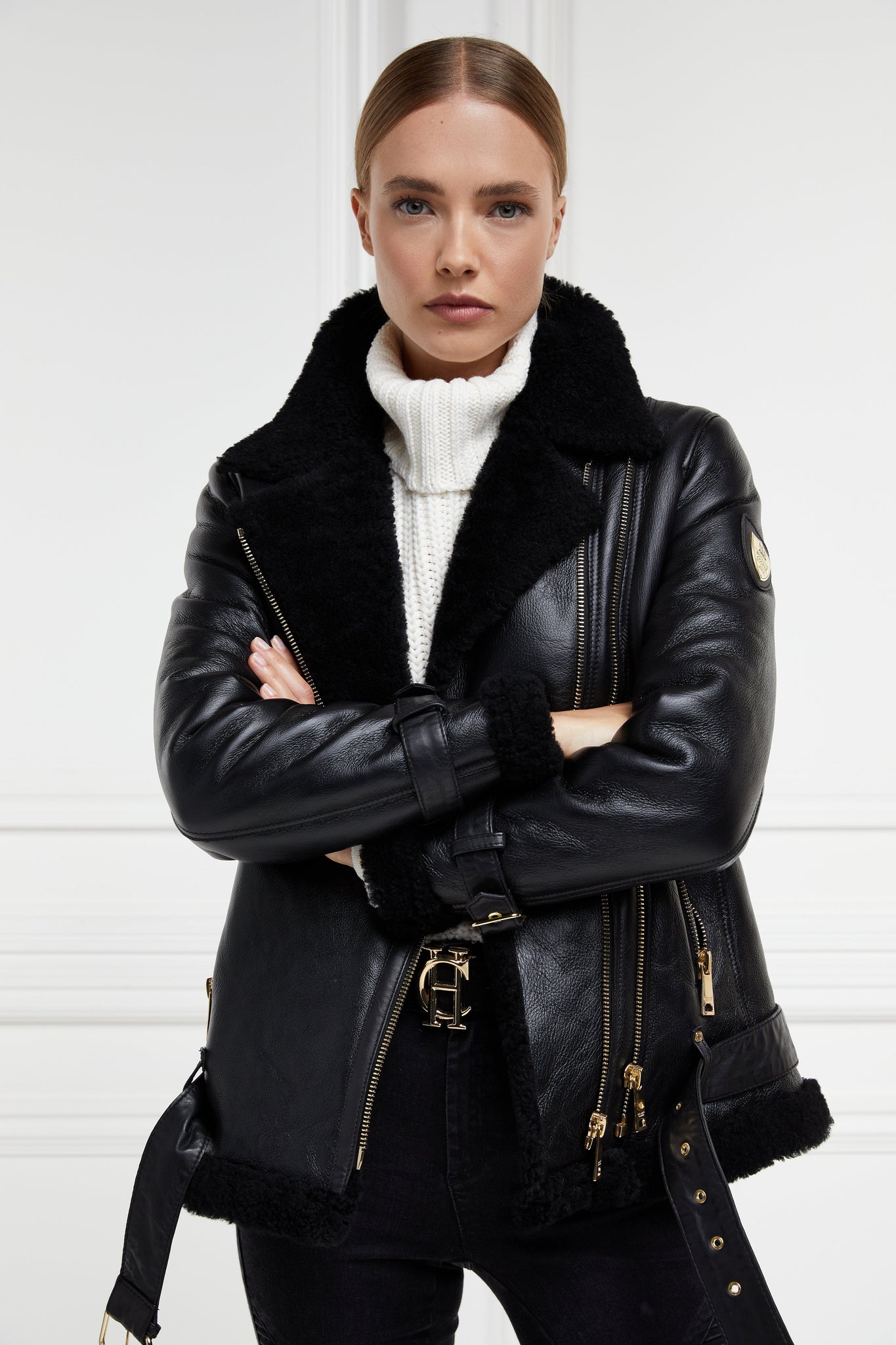 classic aviator jacket in black leather with back shearling inside that accents the cuffs hem and collar with belt detail on the hem and cuffs three pockets and angular zip fastening