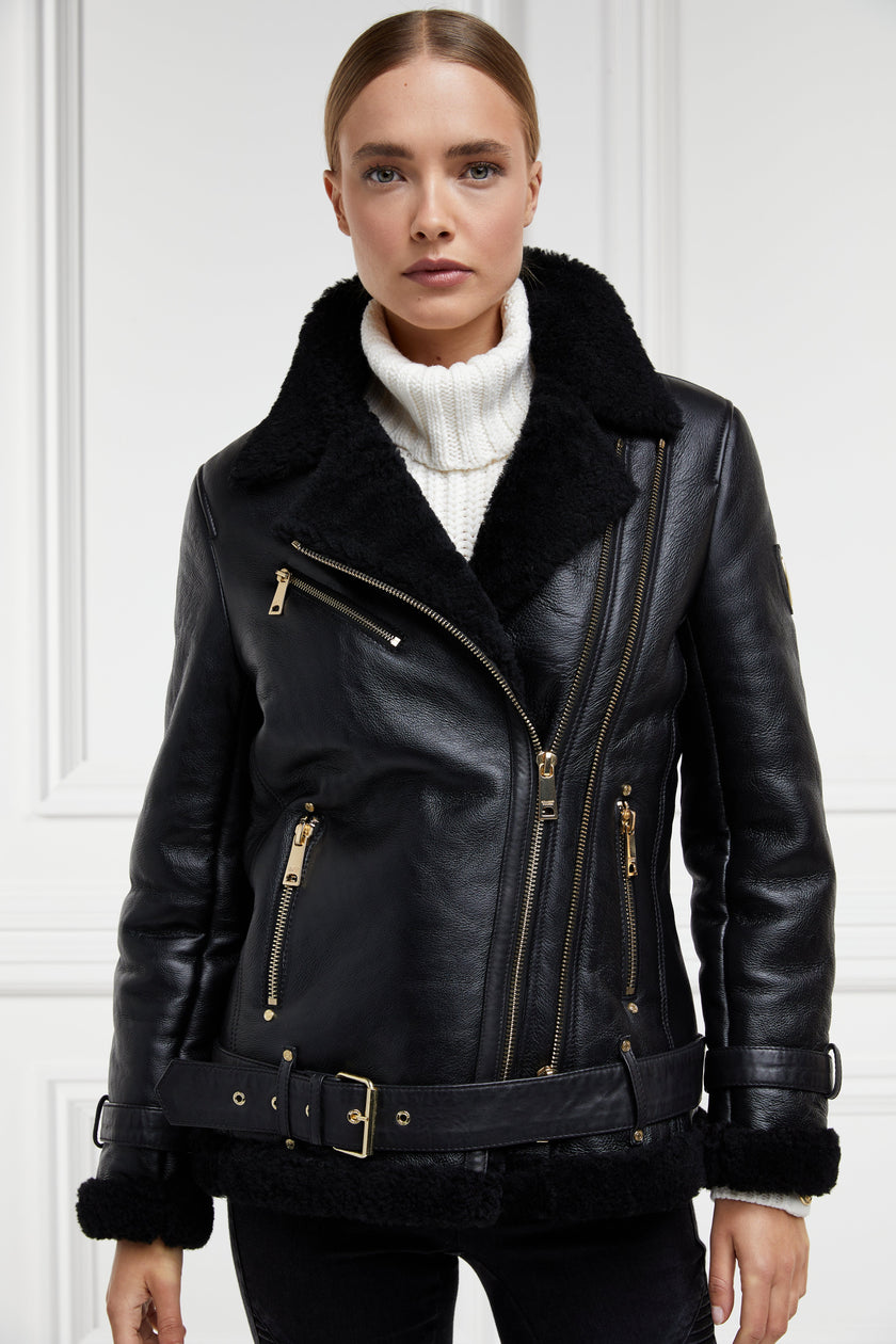 classic aviator jacket in black leather with back shearling inside that accents the cuffs hem and collar with belt detail on the hem and cuffs three pockets and angular zip fastening