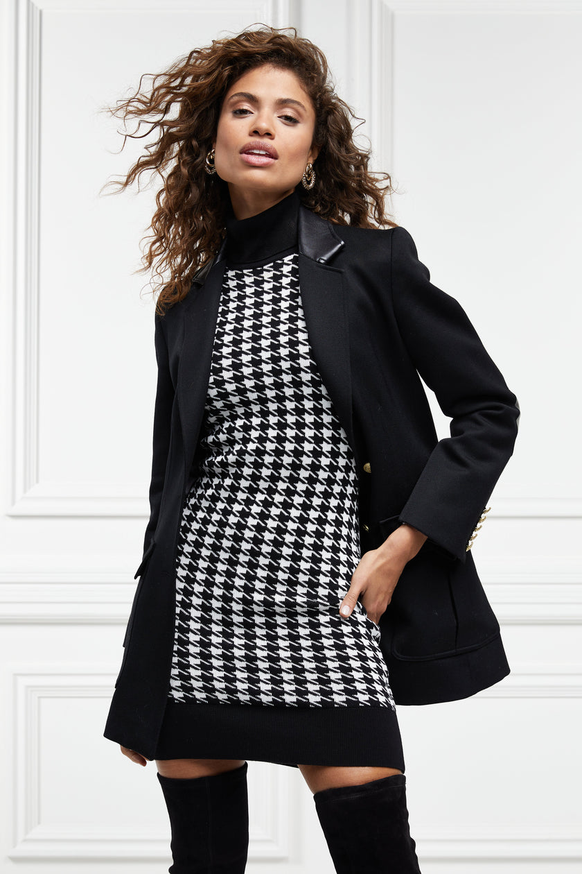 womens black and white houndstooth sleeveless mini dress with black contrast arm holes roll neck and hem with gold button details on shoulders under black double breasted blazer