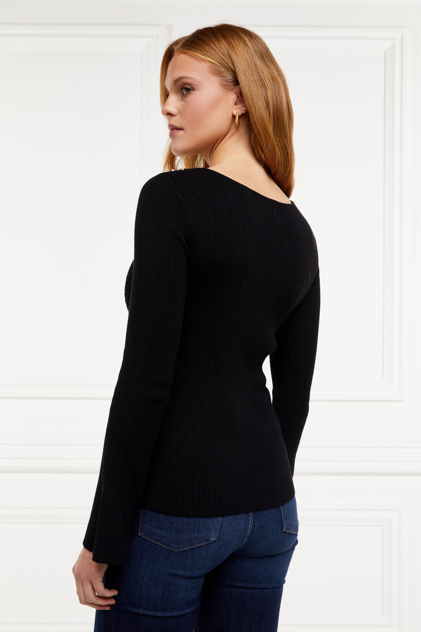 a form fitting lightweight ribbed knit black jumper with a boat neckline and bell sleeves