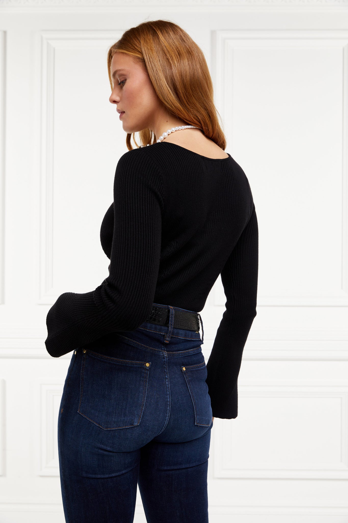 a form fitting lightweight ribbed knit black jumper with a boat neckline and bell sleeves