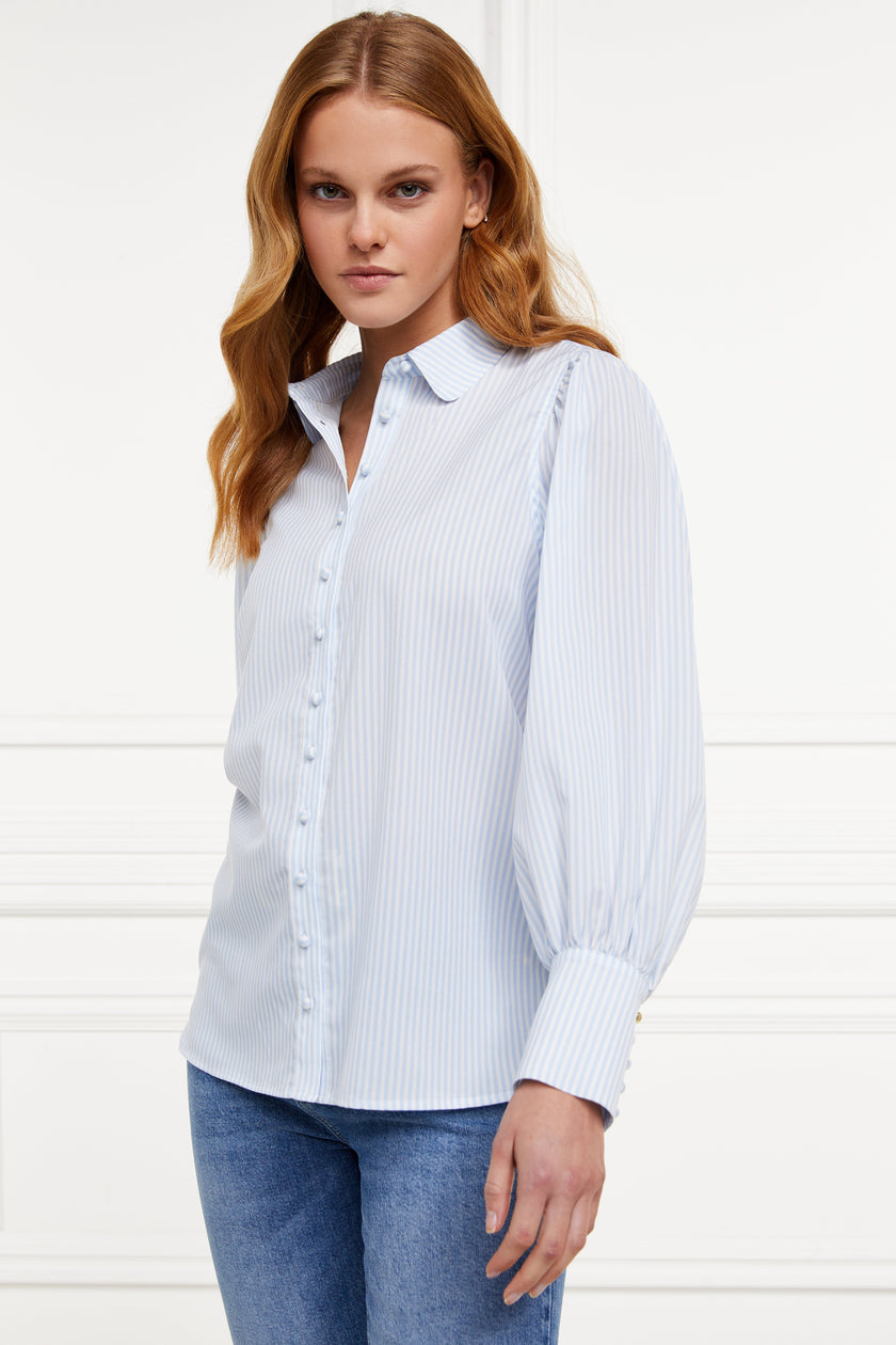 A classic fitted shirt with long sleeves and subtle puffy shoulders with thin blue and white stipe print design with extra long cuffs and rounded collar detailed with fabric buttons 