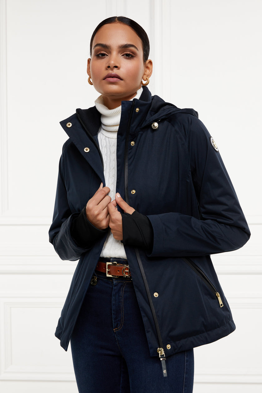 Womens waterproof navy jacket with stowaway hood storm cuffs and two pockets at hip with waterproof zip fastening