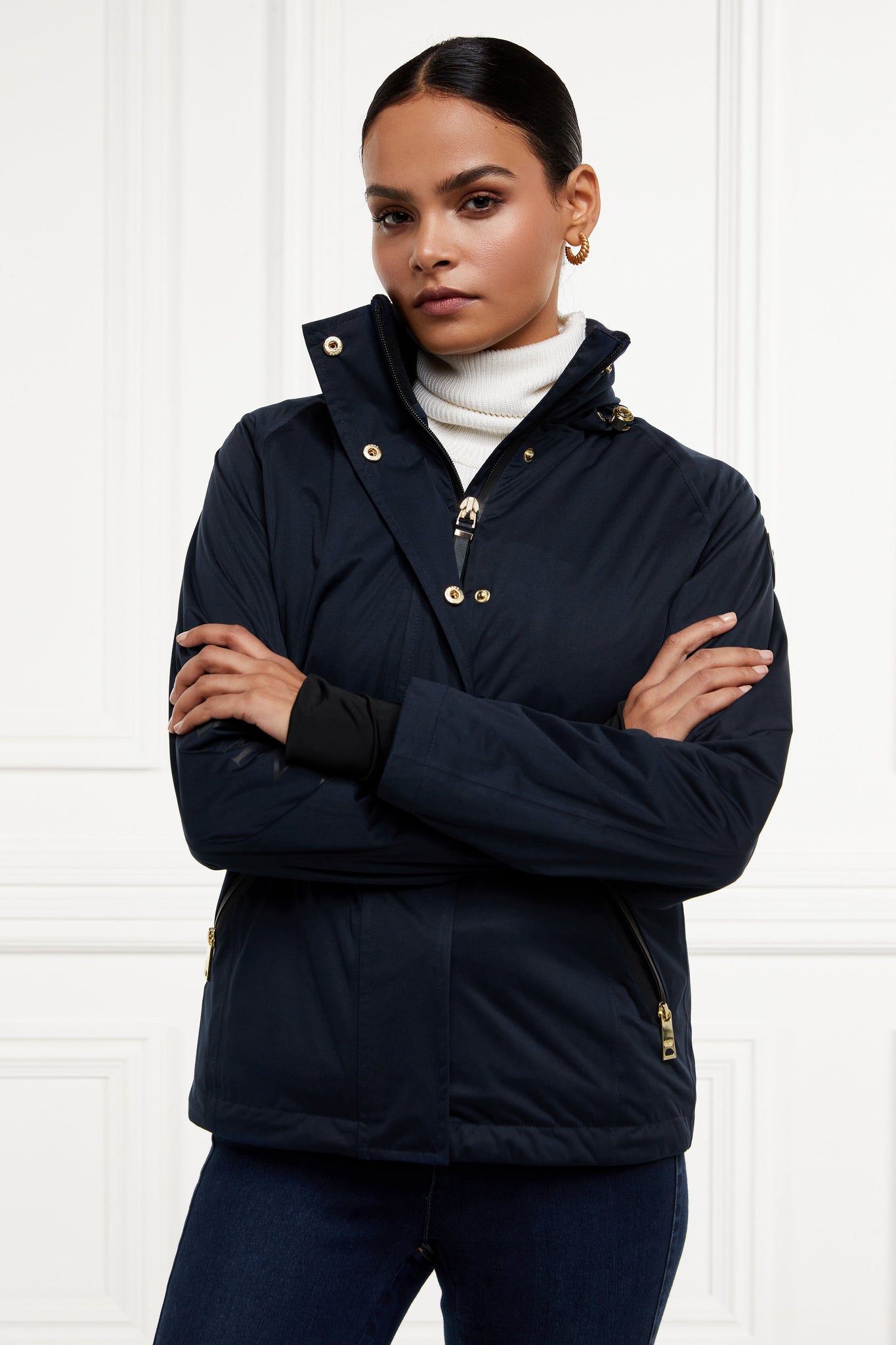 Womens waterproof navy jacket with stowaway hood storm cuffs and two pockets at hip with waterproof zip fastening