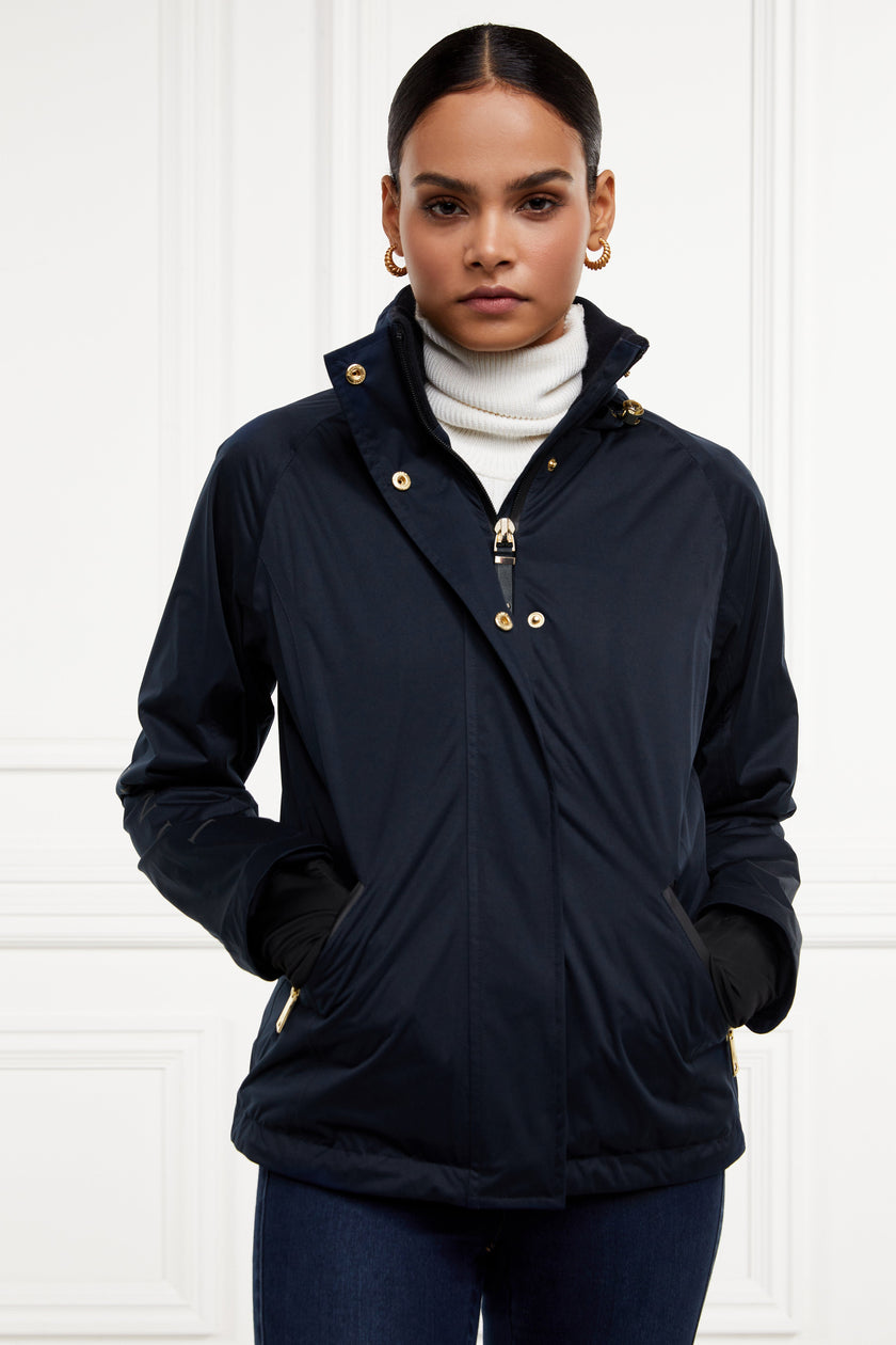 Womens waterproof navy jacket with stowaway hood storm cuffs and two pockets at hip with waterproof zip fastening