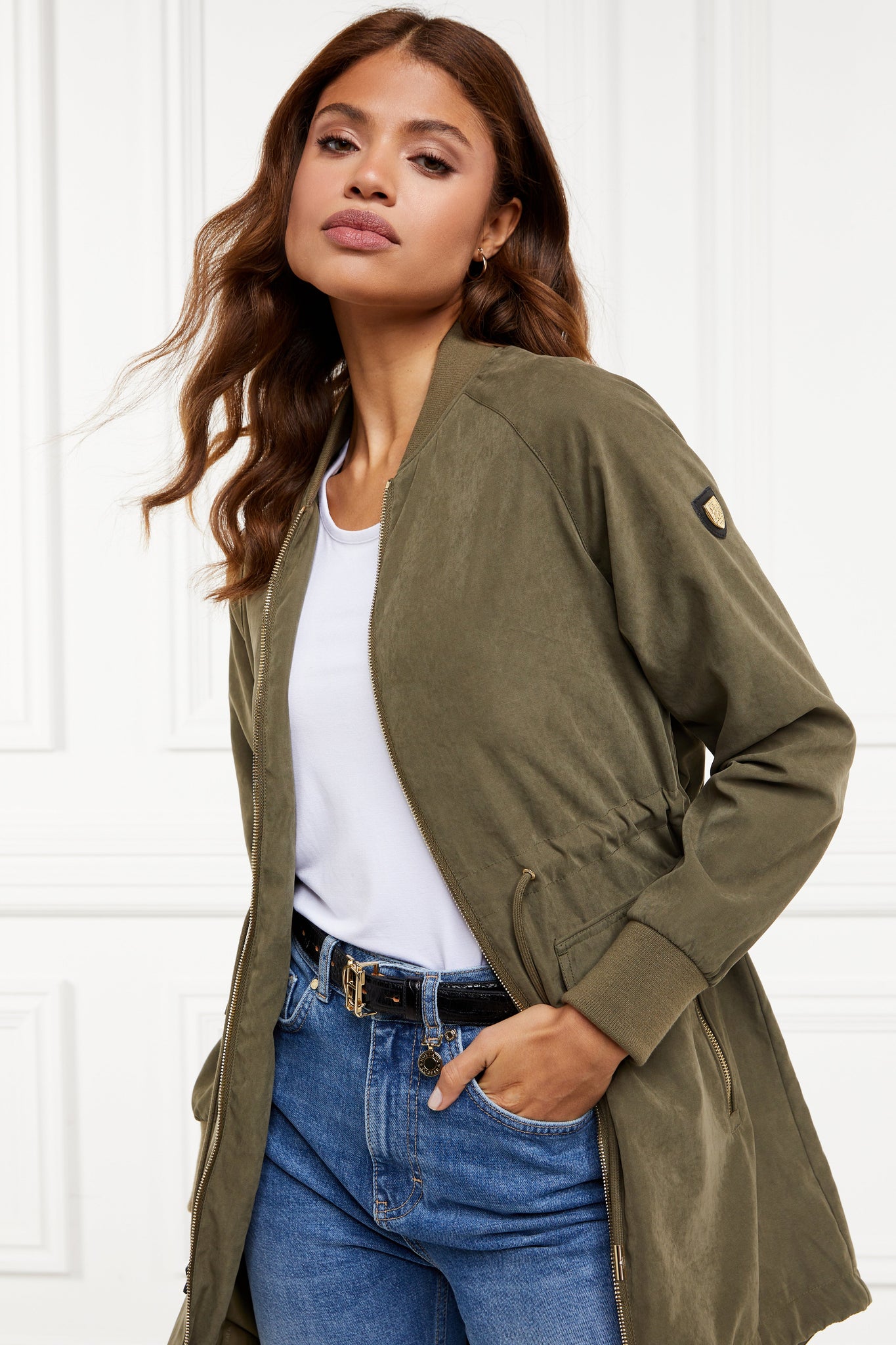 brushed suede longline lightweight parka jacket in khaki with an adjustable drawstring waist and fishtail hem and ribbed baseball style jersey collar and cuffs finished with gold hardware and gold shield on sleeve