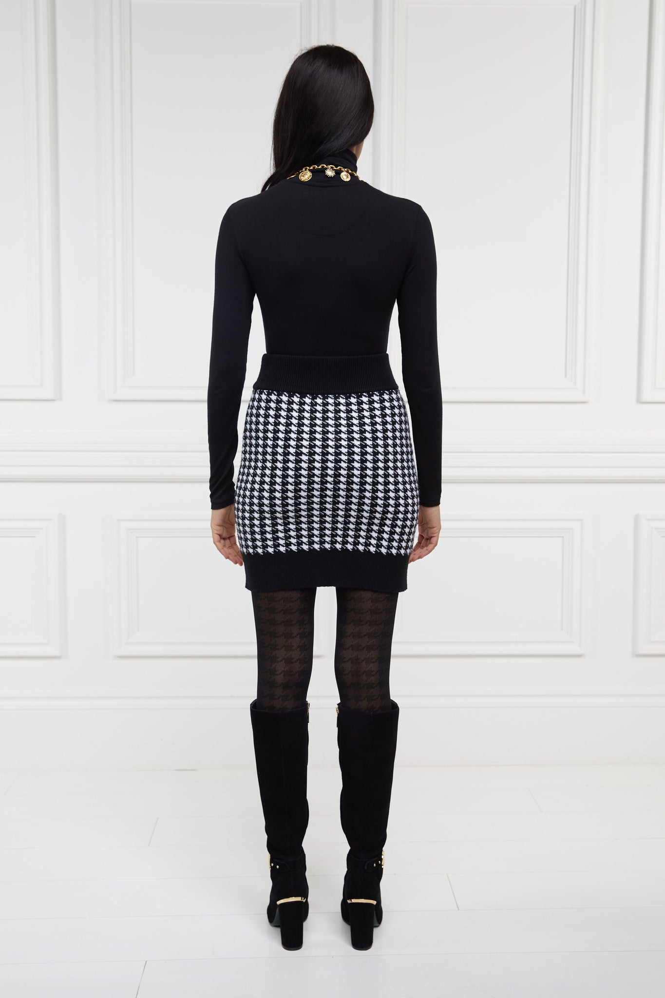 back of womens knitted mini skirt in back and white houndstooth pattern with contrast ribbed waistband centre front panel welt pockets and hem with gold button detail down the front and on each pocket