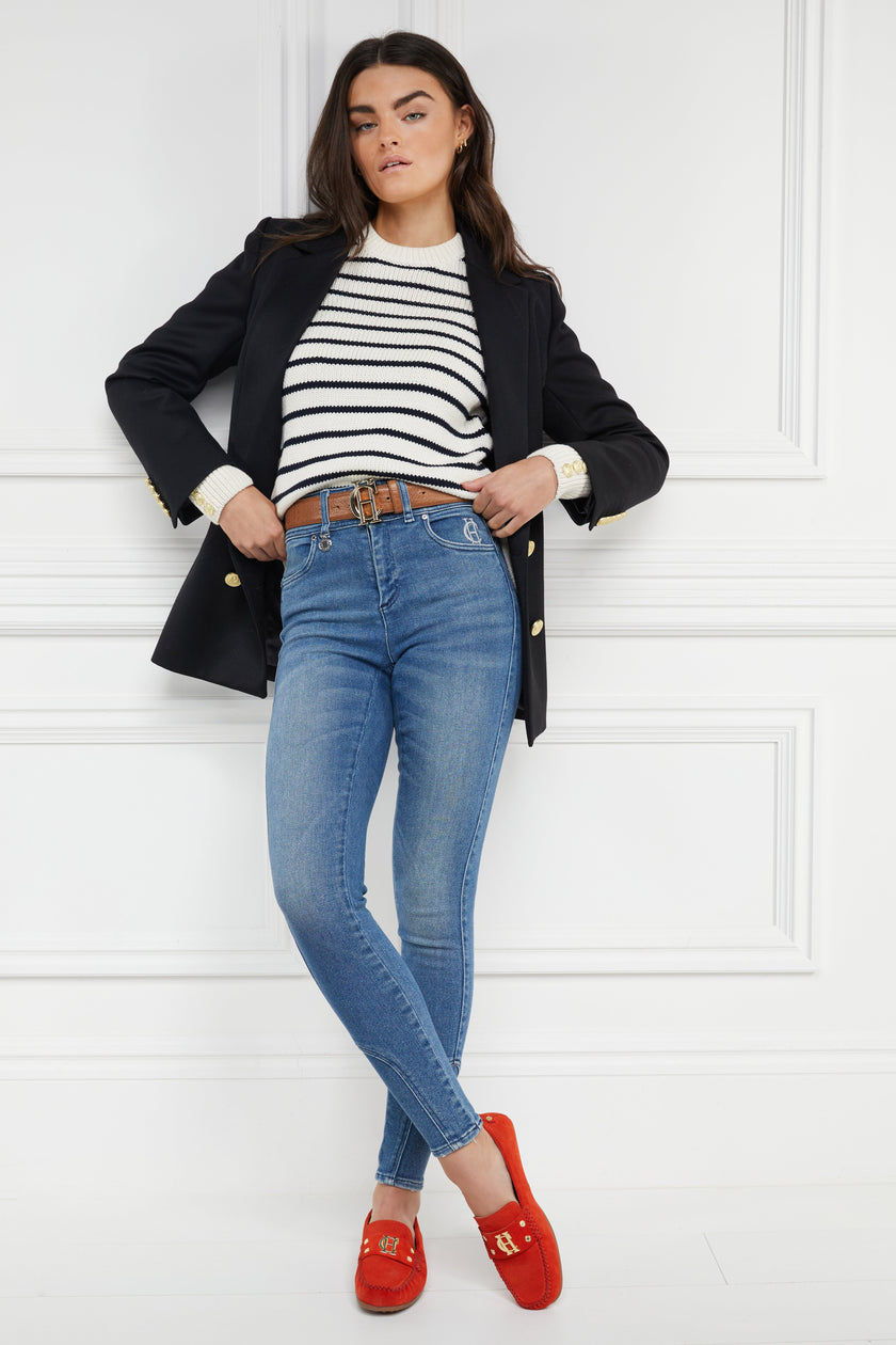 orange suede loafers with a leather sole and top stitching details and gold hardware paired with denim jeans, cream striped crew neck under a navy blazer