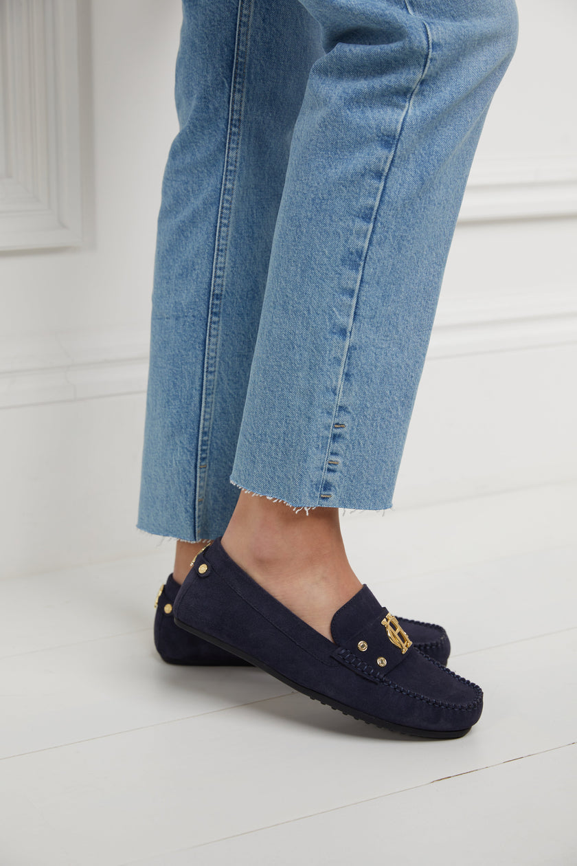 navy suede loafers with a leather sole and top stitching details and gold hardware paired with denim slim jeans