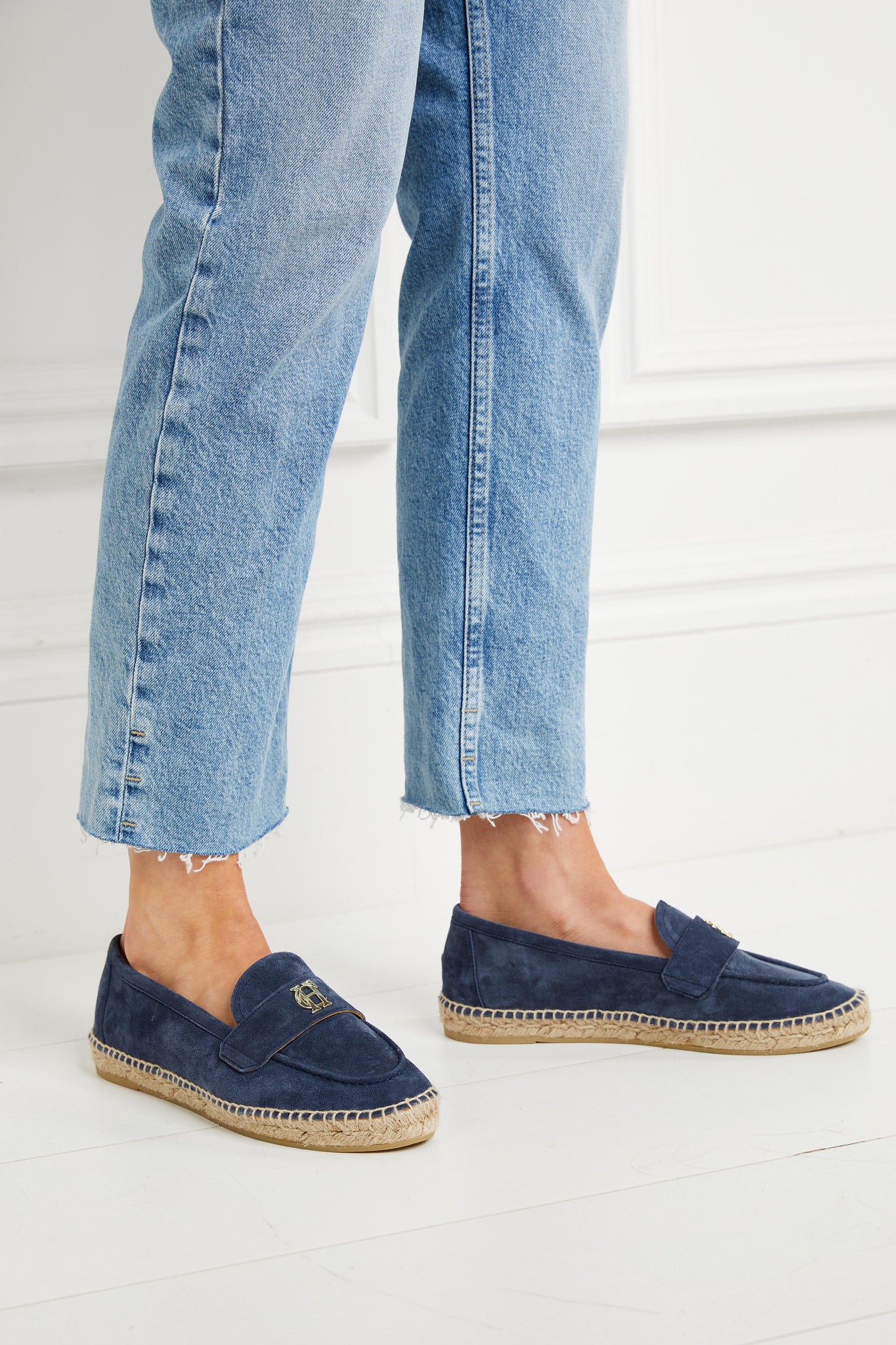 Blue suede espadrille with a natural straw sole and gold hardware on top paired with denim straight jeans with frayed hems