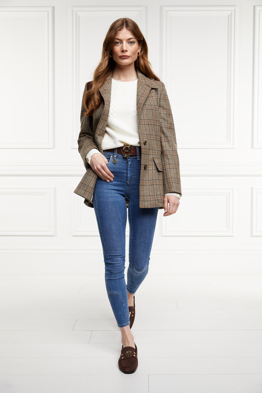 Classic brown suede loafers with a leather sole and top stitching details and gold hardware paired with skinny denim jeans, brown belt, cream crew neck knit and bredon tweed blazer