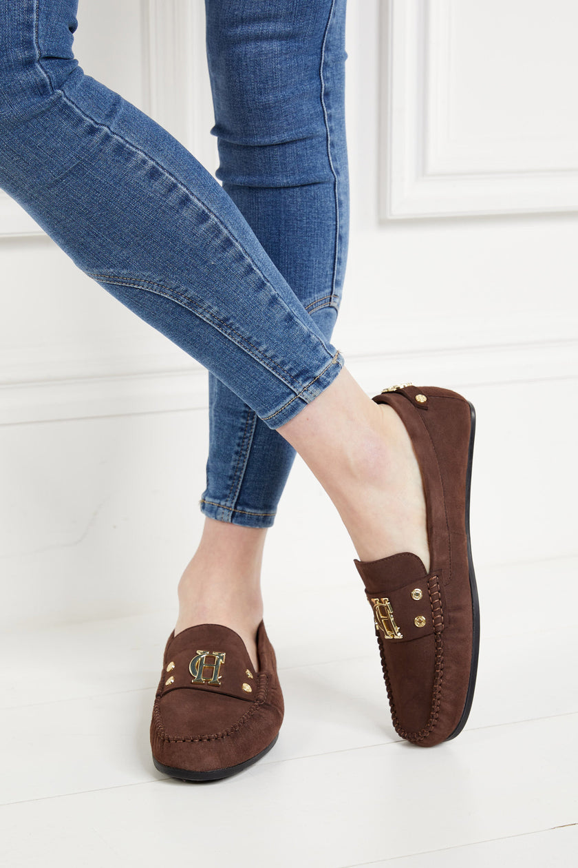 Classic brown suede loafers with a leather sole and top stitching details and gold hardware with skinny denim jeans