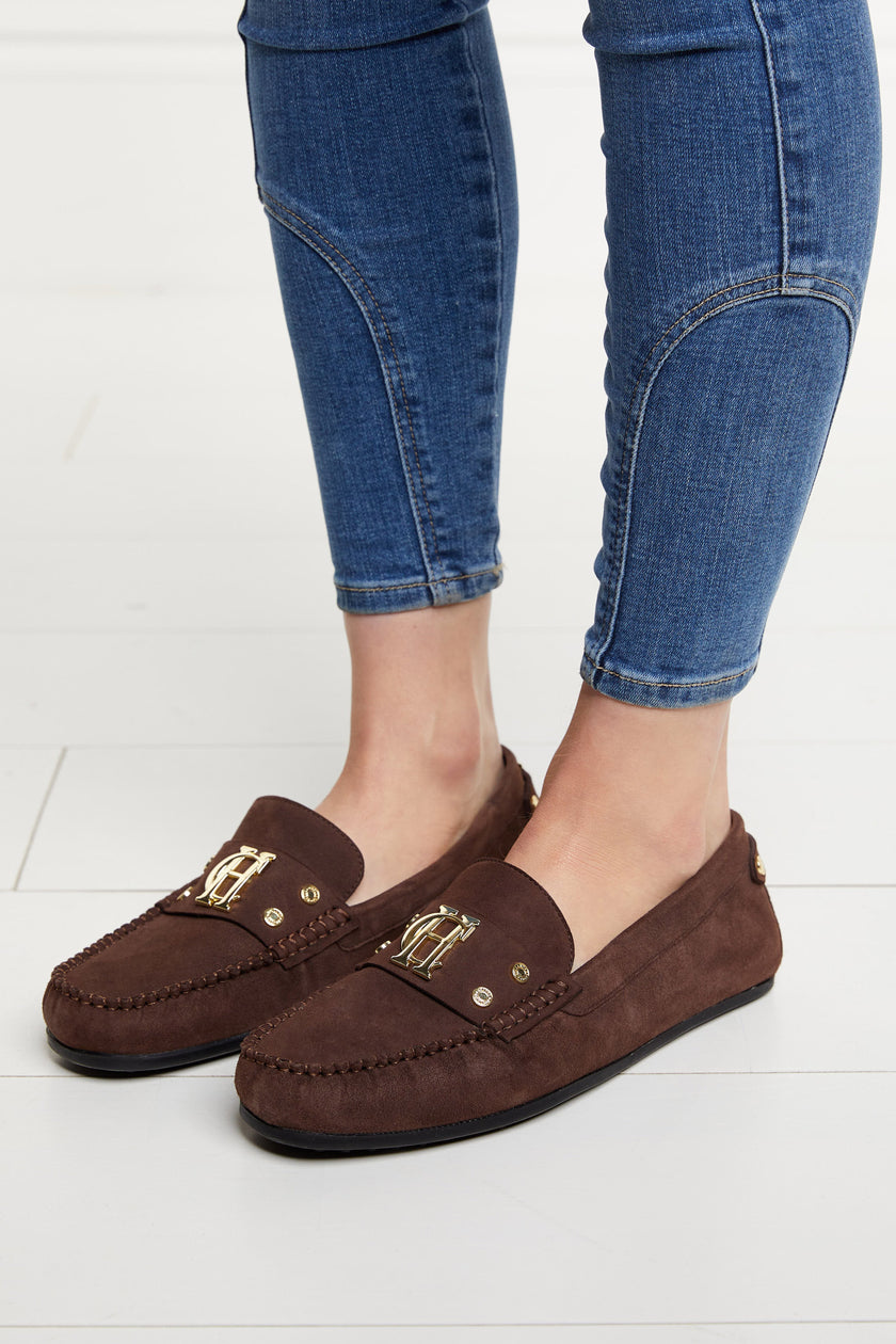 Classic brown suede loafers with a leather sole and top stitching details and gold hardware with skinny denim jeans