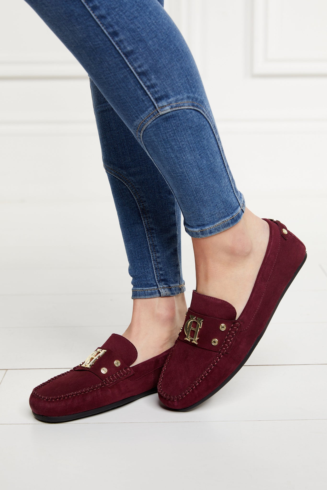 classic deep red suede loafers with a leather sole and top stitching details and gold hardware paired with skinny denim jeans