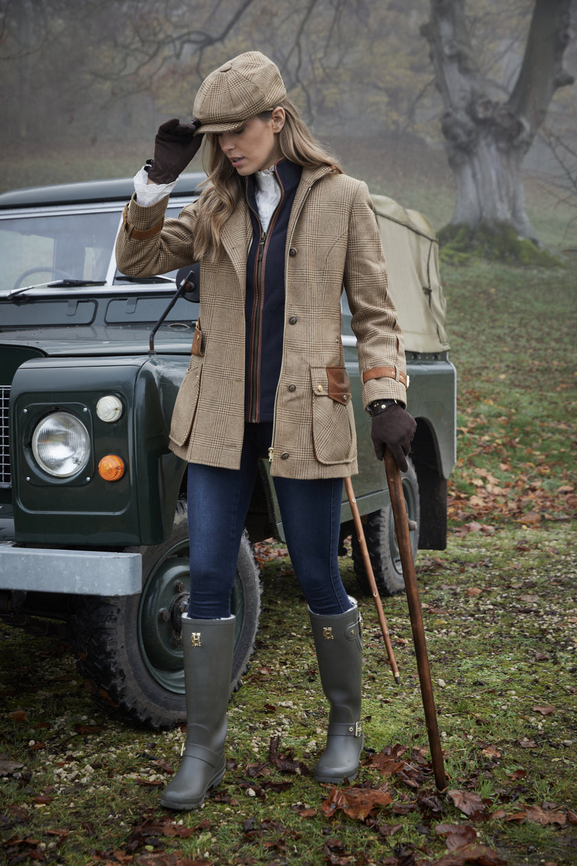 Woman in tan brown tartan tweed field coat and baker boy cap