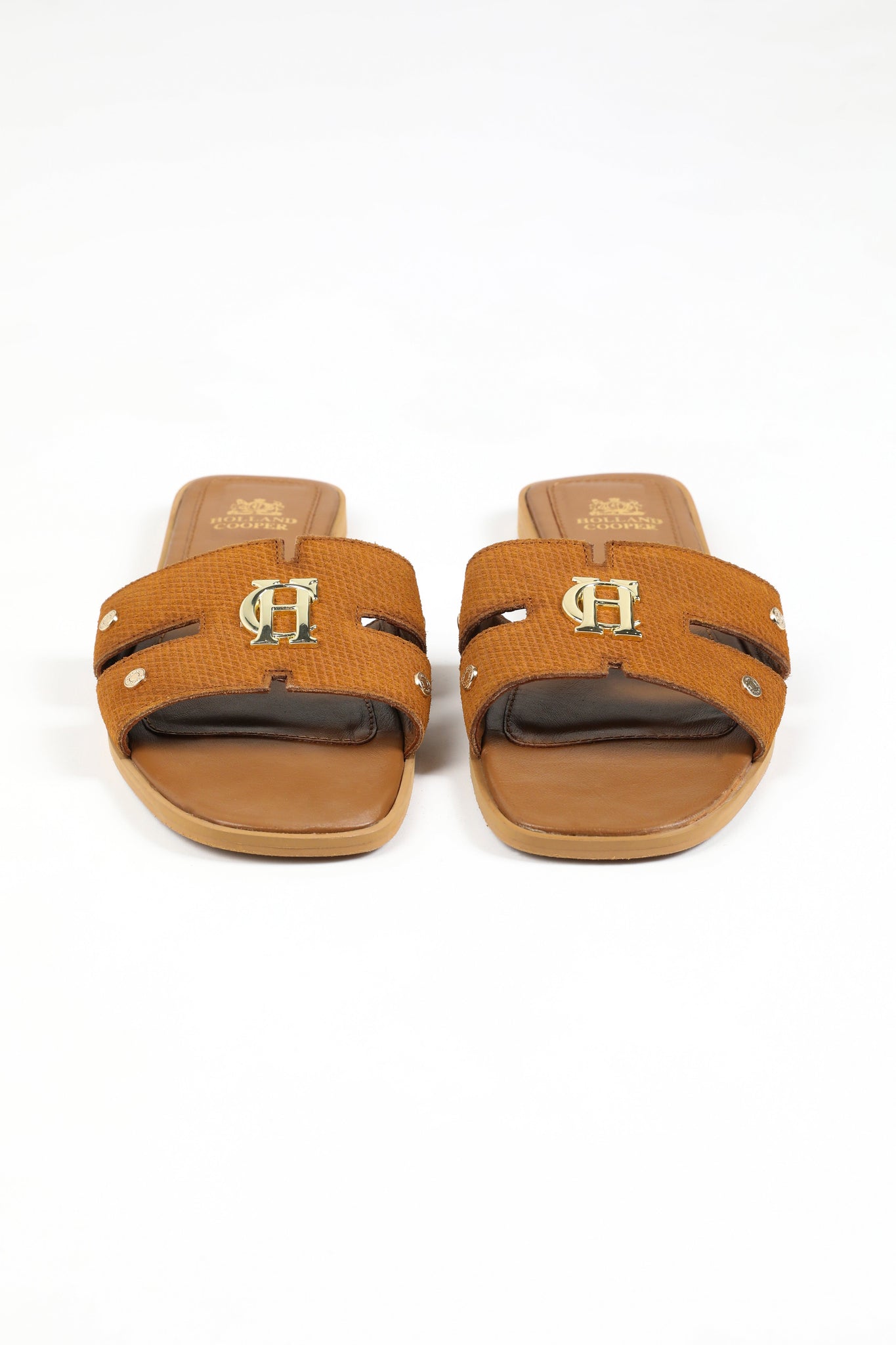 Front shot of tan suede sliders with a tan branded leather sole and gold hardware. 