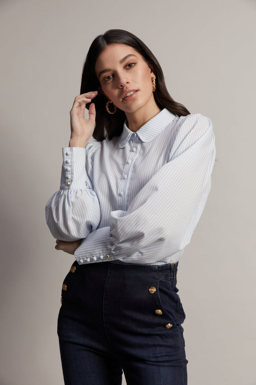 A classic fitted shirt with long sleeves and subtle puffy shoulders with thin blue and white stipe print design with extra long cuffs and rounded collar detailed with fabric buttons 