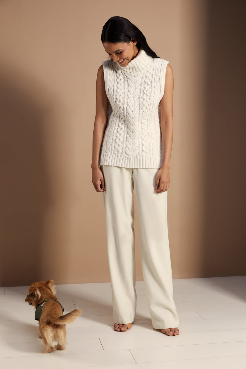 Sleeveless white chunky knit cable jumper with a roll neck and ties at each side 