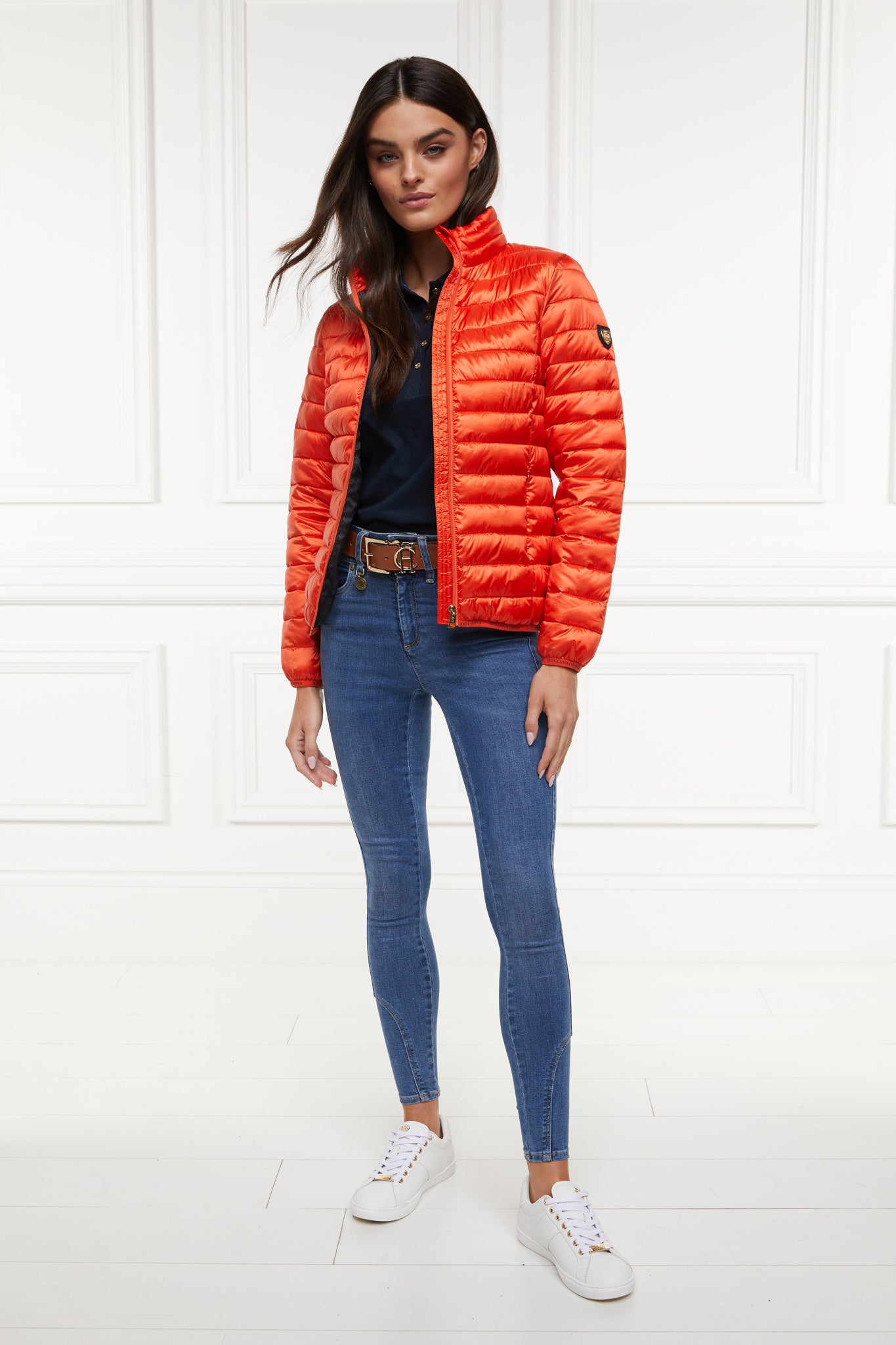 womens lightweight hoodless padded orange jacket with embroidery detail on back high neck and elasticated cuffs and hem. easily packs away into separate small bag of the same colour with handle 