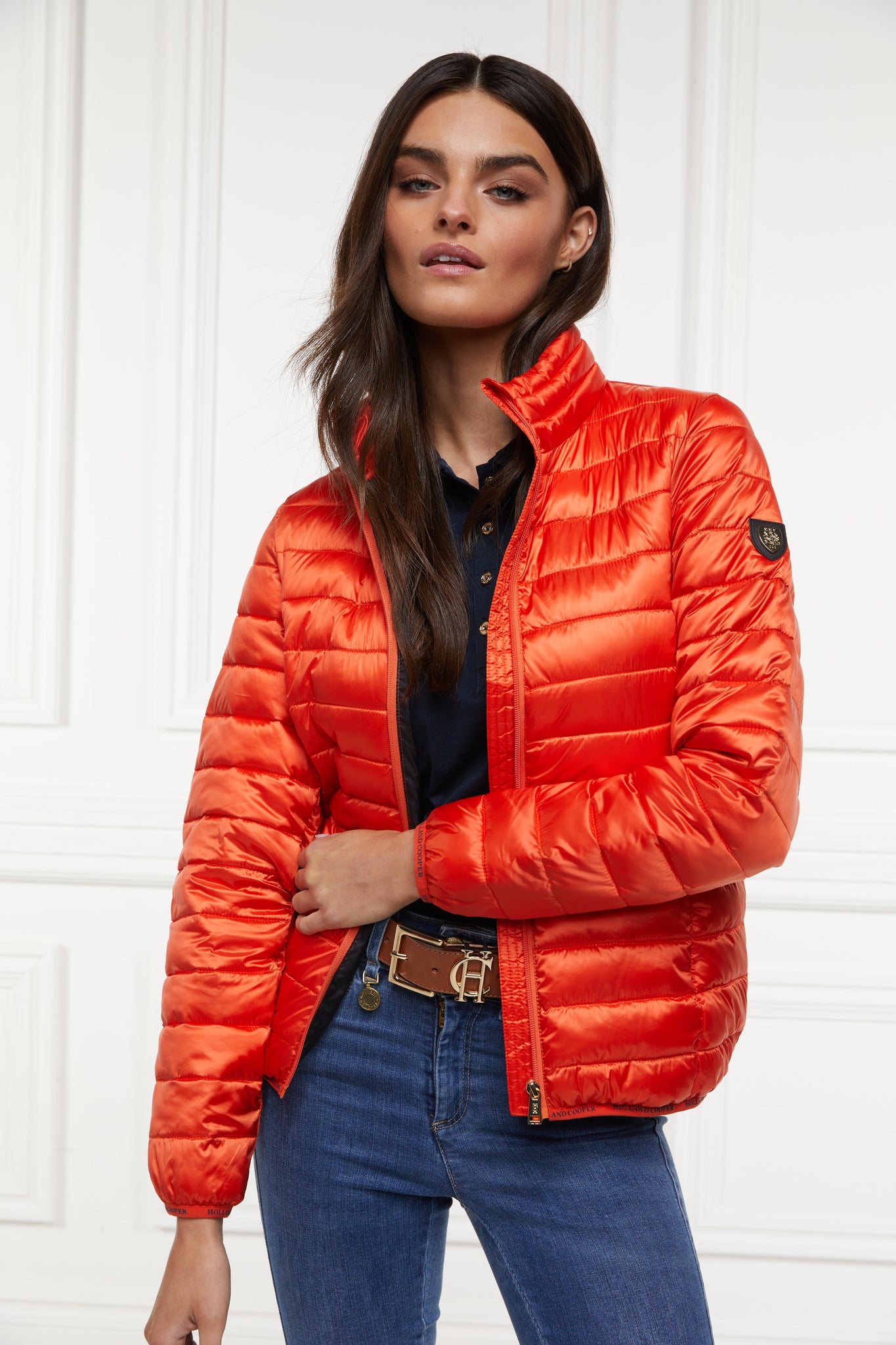 womens lightweight hoodless padded orange jacket with embroidery detail on back high neck and elasticated cuffs and hem. easily packs away into separate small bag of the same colour with handle 