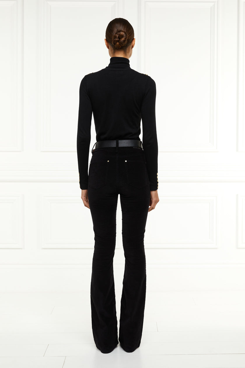 back of womens high rise black velvet flared jeans with centre front zip fly fastening with two open pockets at the front and back with gold stirrup charm to the belt loop