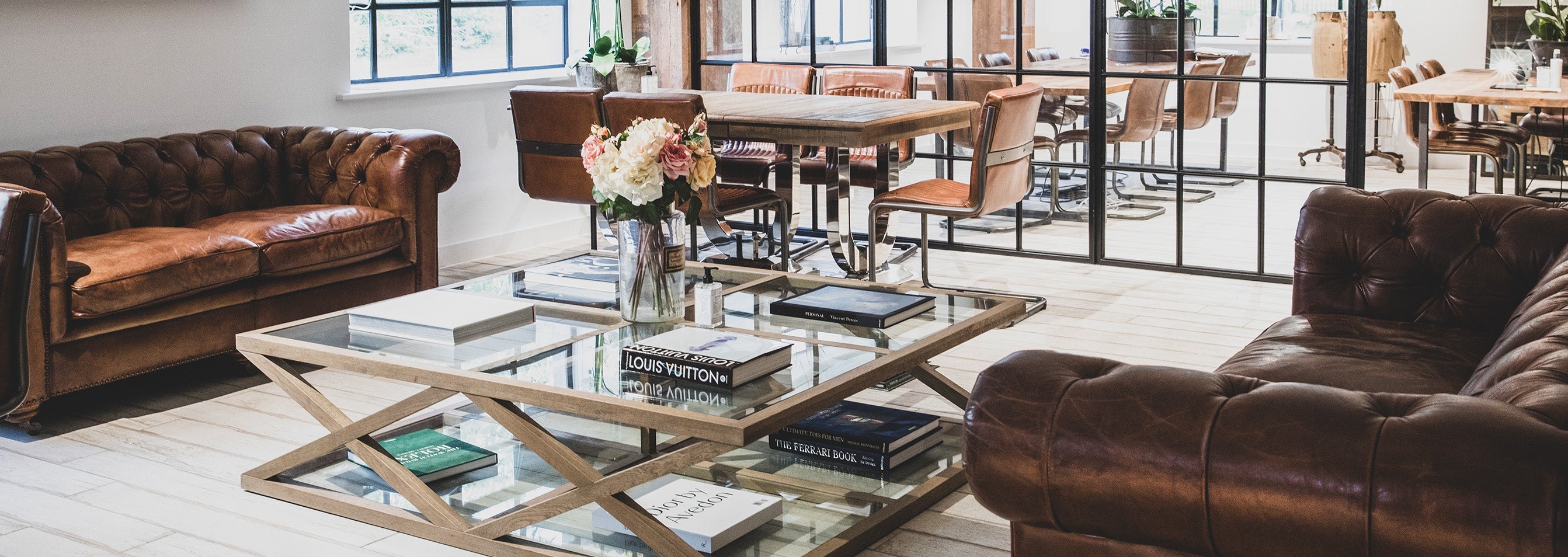 Holland Cooper Office with two leather sofas in between a glass coffee table with wooden edges laden with coffee table books