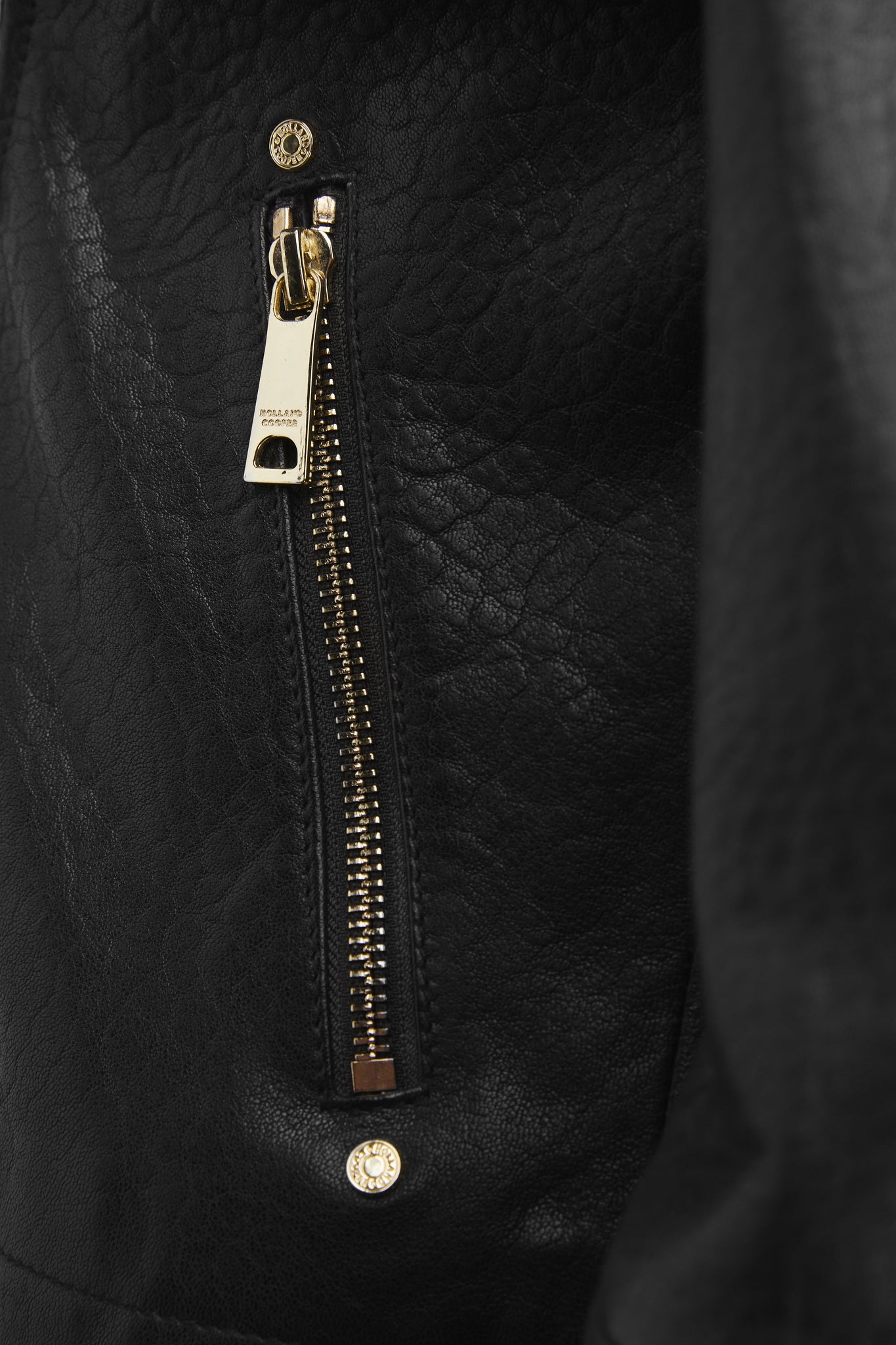 gold zip pocket detail on womens leather biker jacket in black with fringing along the back and sleeves detailed with golf zips and small shield badge on arm