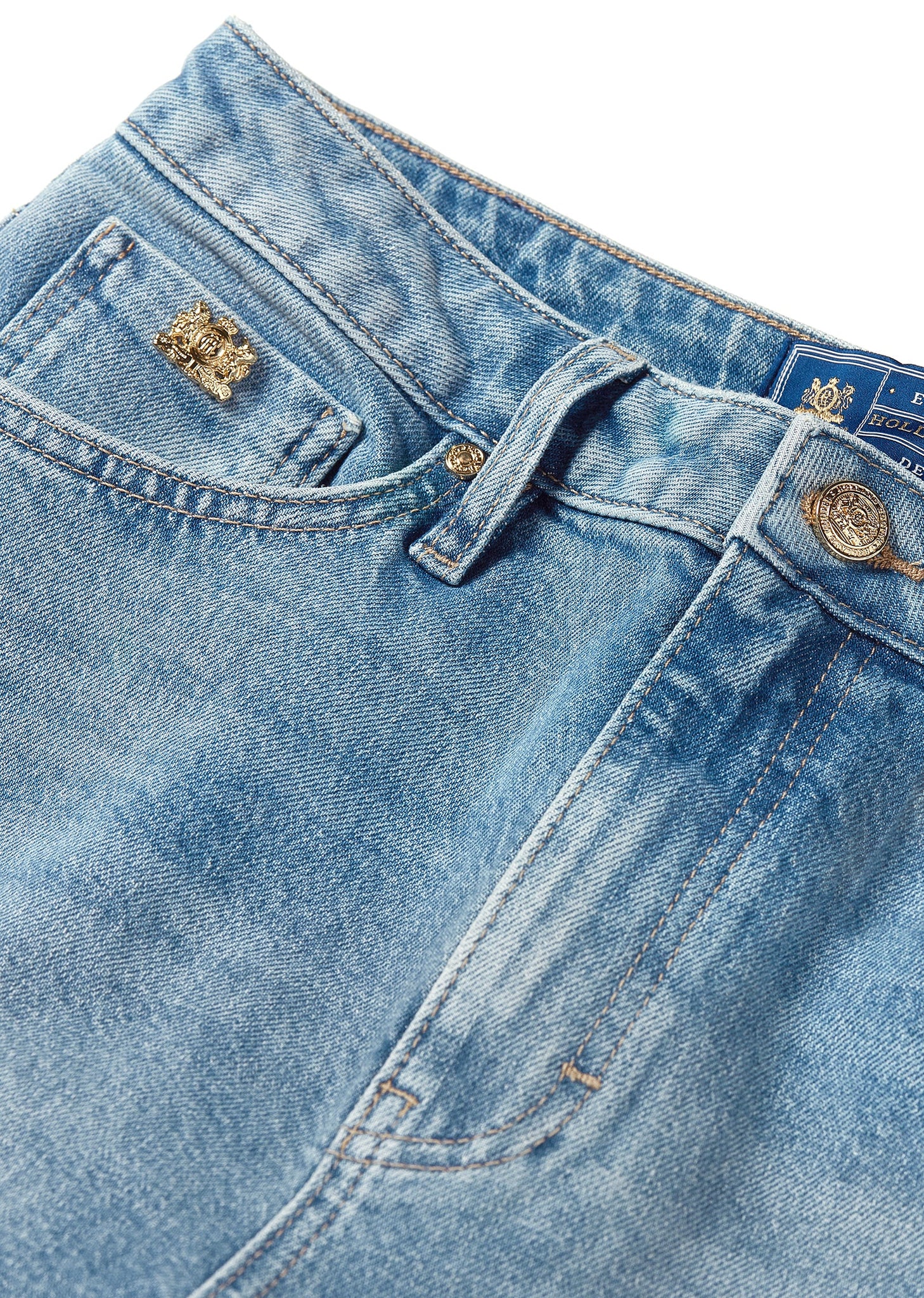 front pocket detail on womens high rise blue denim slim fit jean with raw hem and two open pockets on the front and back with gold stirrup charm to the belt loop