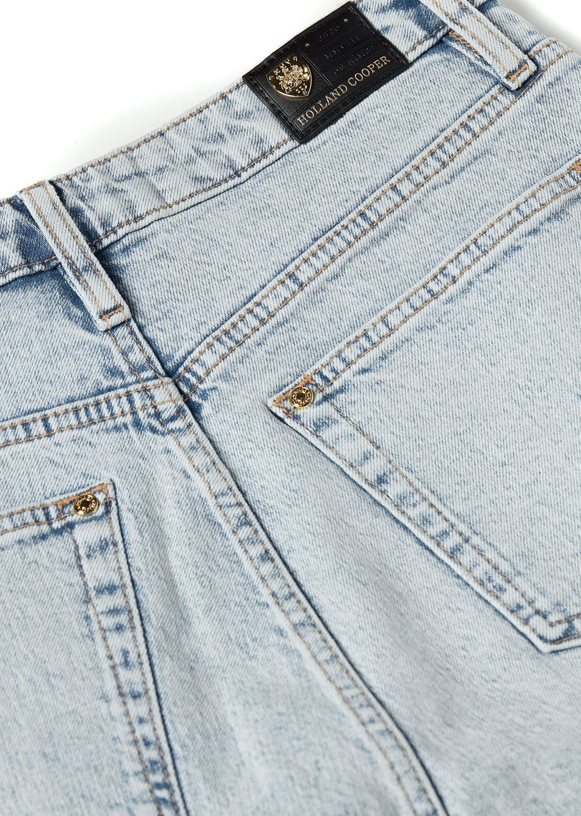 back pocket detail on womens high rise light blue denim slim fit jean with raw hem and two open pockets on the front and back with gold stirrup charm to the belt loop