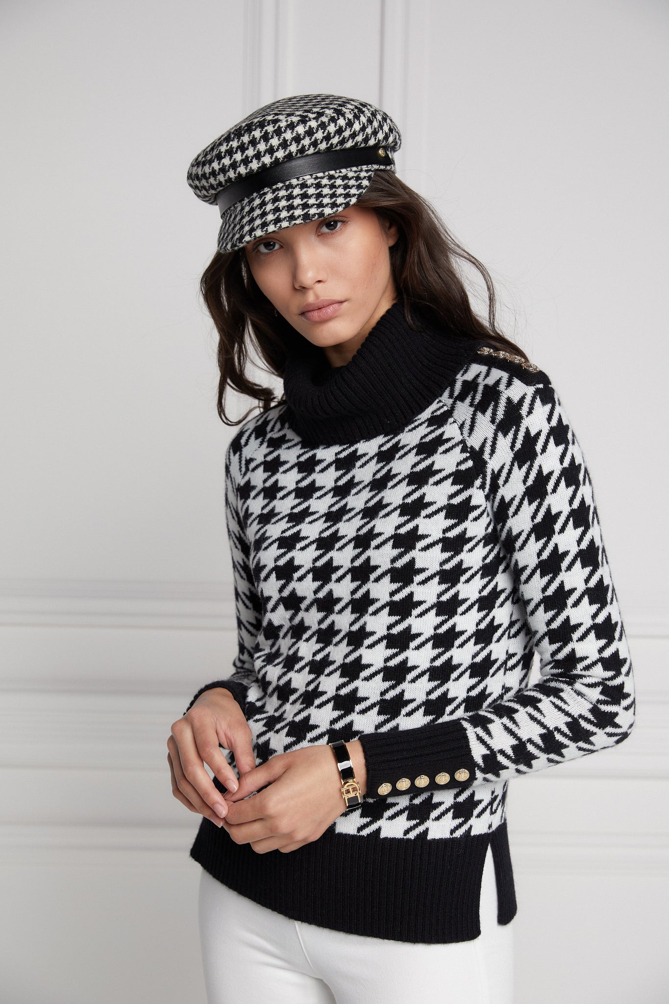 a classic black and white houndstooth jumper with contrast black cuffs, roll neck and split ribbed hem with gold button detail on the cuffs and collar