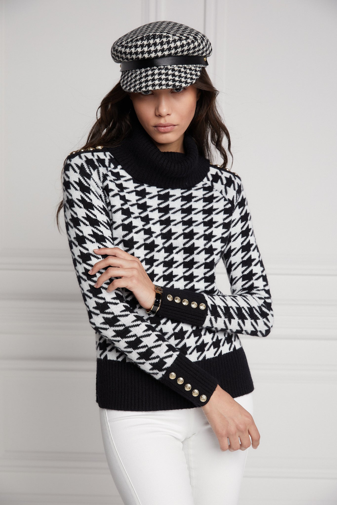 a classic black and white houndstooth jumper with contrast black cuffs, roll neck and split ribbed hem with gold button detail on the cuffs and collar