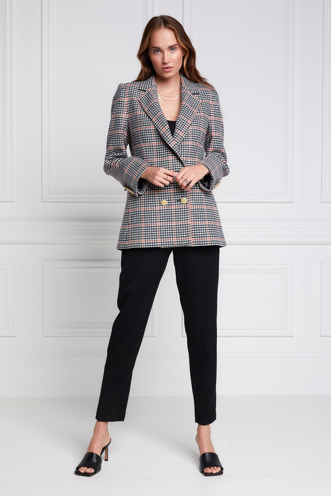 double breasted wool blazer in black white and pink check with two hip pockets and gold button details down front and on cuffs and handmade in the uk worn with black tailored trousers