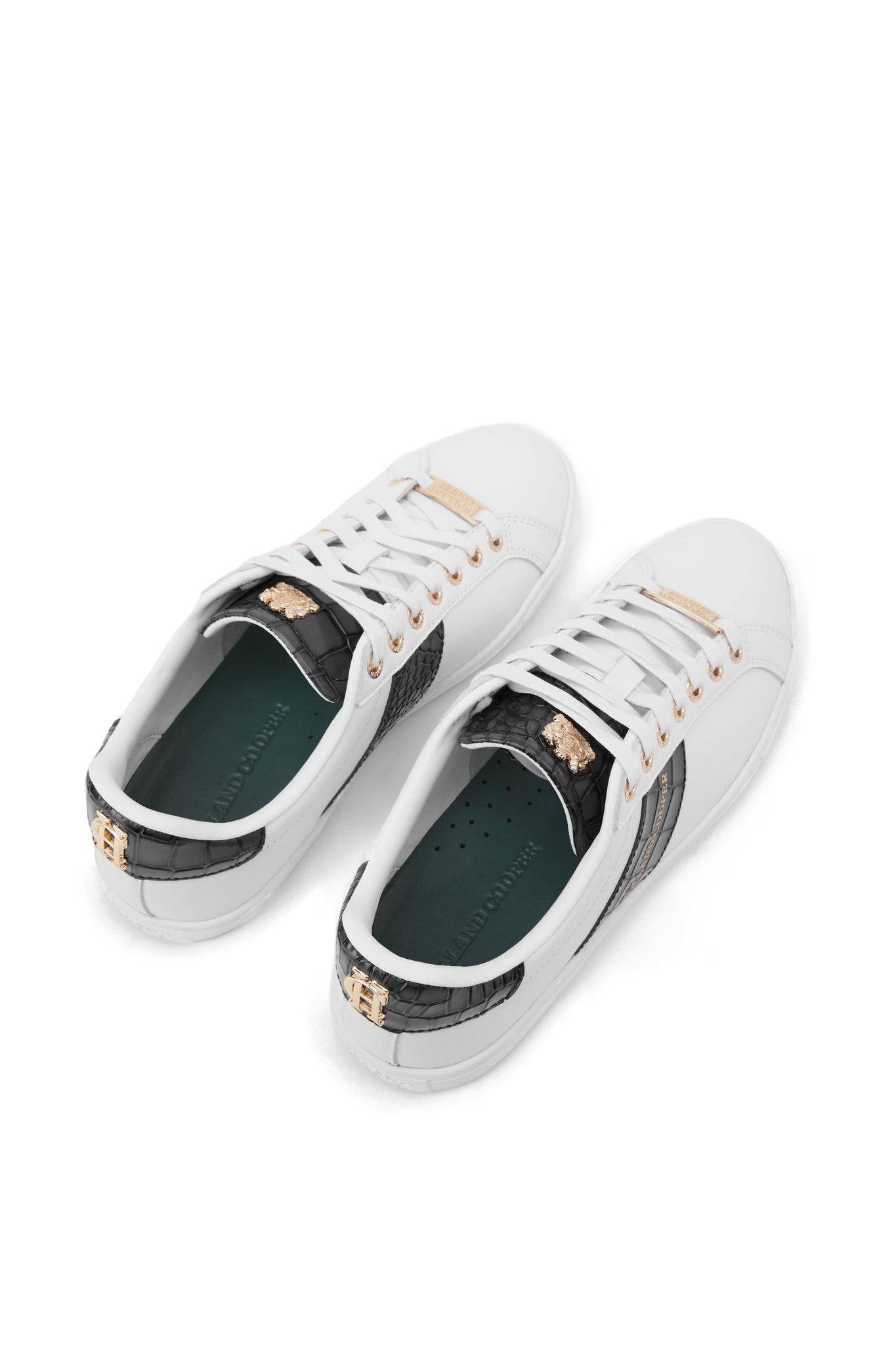 Birds eye view of white leather trainers with white laces detailed with a diagonal stripe of black croc embossed leather with gold foil branding and a black croc embossed leather tongue and heel with gold hardware