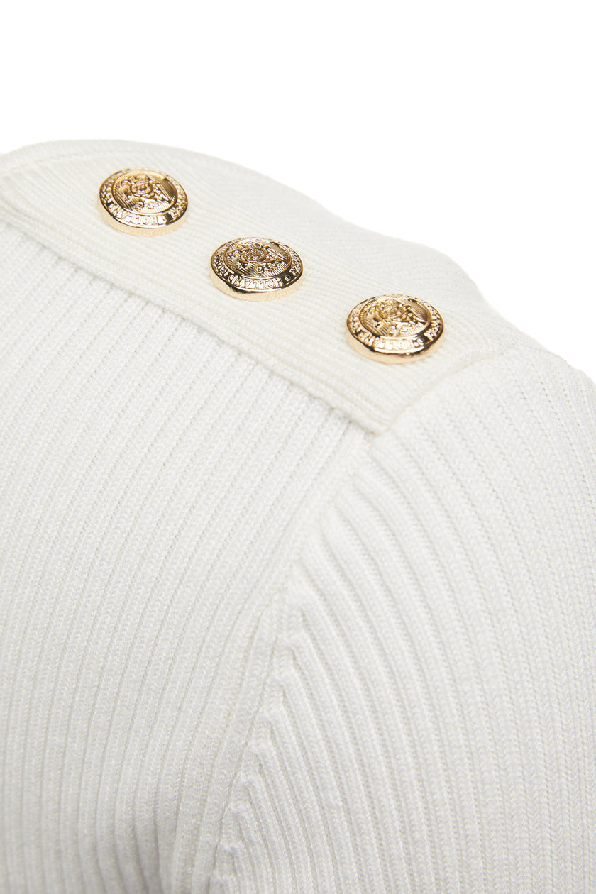 gold button detail accross shoulders of a form fitting finely ribbed long sleeved knitted top in cream with a sweetheart neckline 