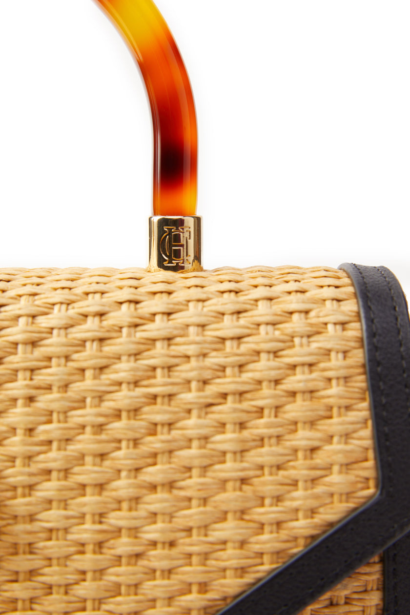 close up detail shot of acetate tortoiseshell effect top handle with gold hardware on natural raffia bag