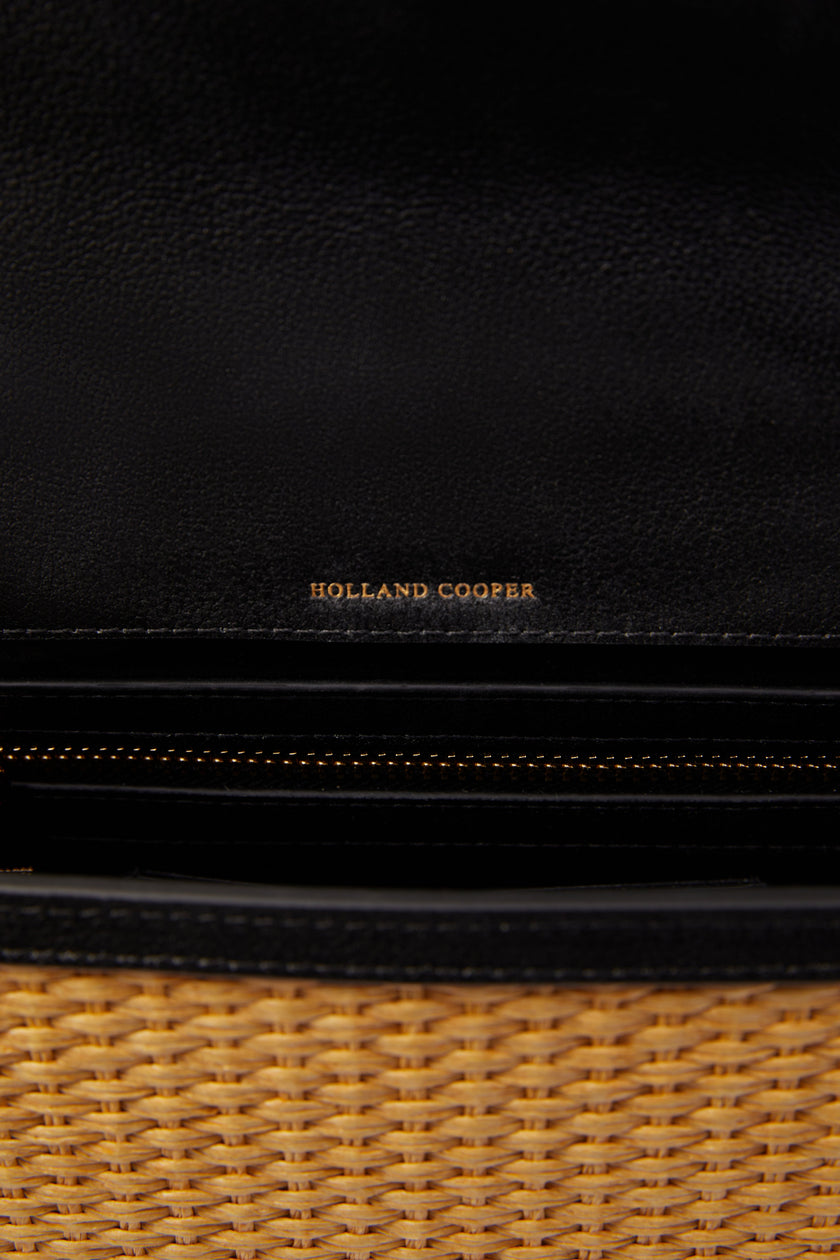 Close up inside natural raffia bag showing black interal lining with internal card slots and a zip pocket