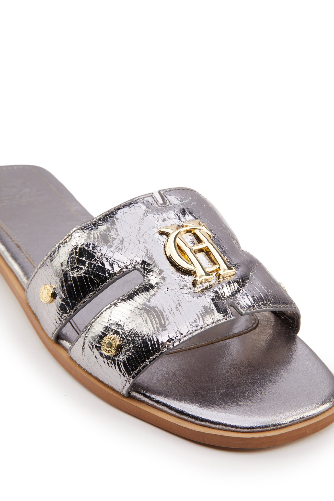 close up shot of Silver leather sliders with crackled effect and a tan leather sole and gold hardware