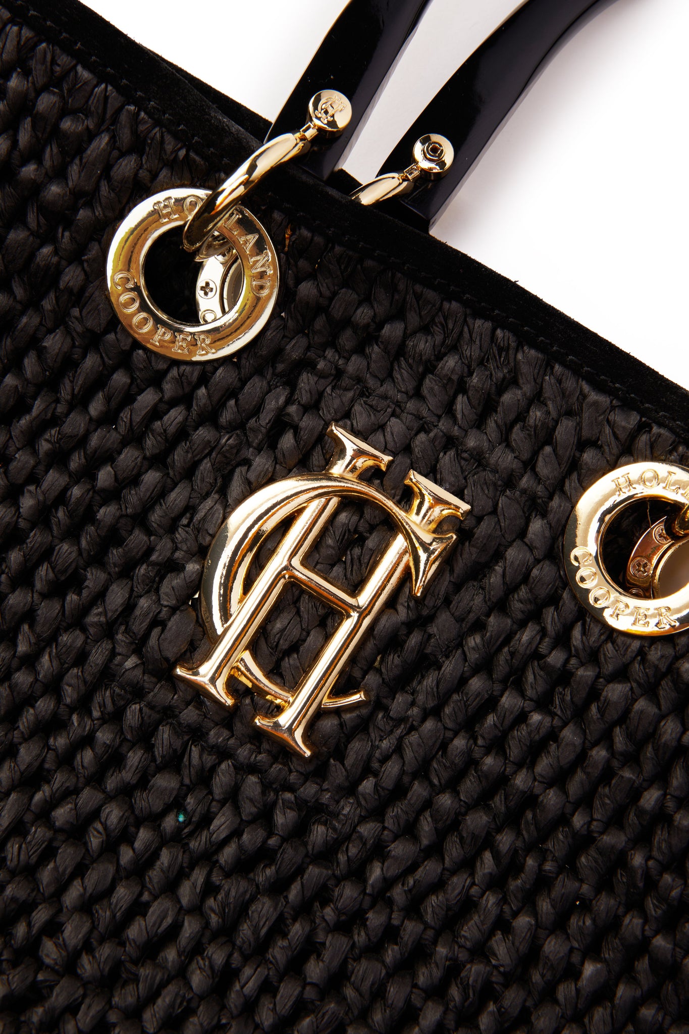 close up of gold hardware details on black raffia tote bag