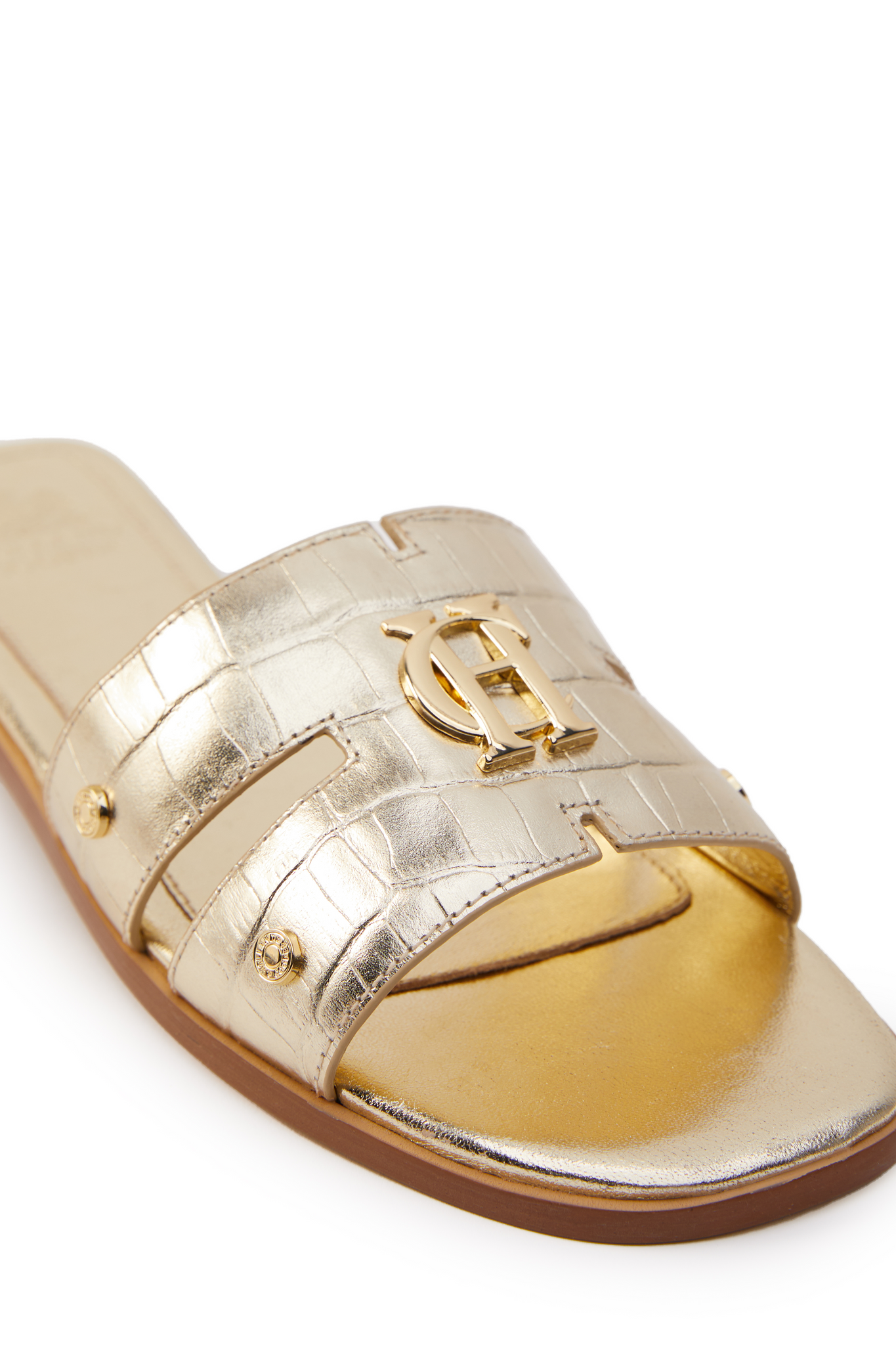 Close up of gold croc embossed leather sliders with a tan leather sole and gold hardware.