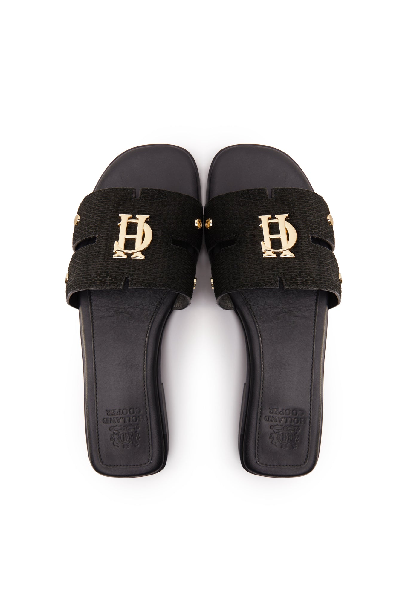 Birds eye view of black suede sliders with a black leather sole and gold hardware. 