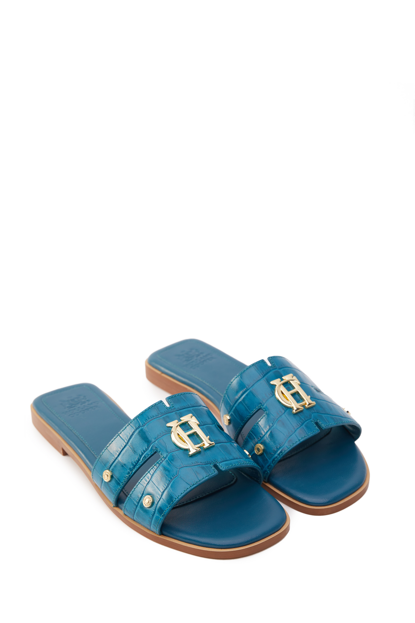 side view of Teal blue croc embossed leather sliders with  a tan leather sole and gold hardware.