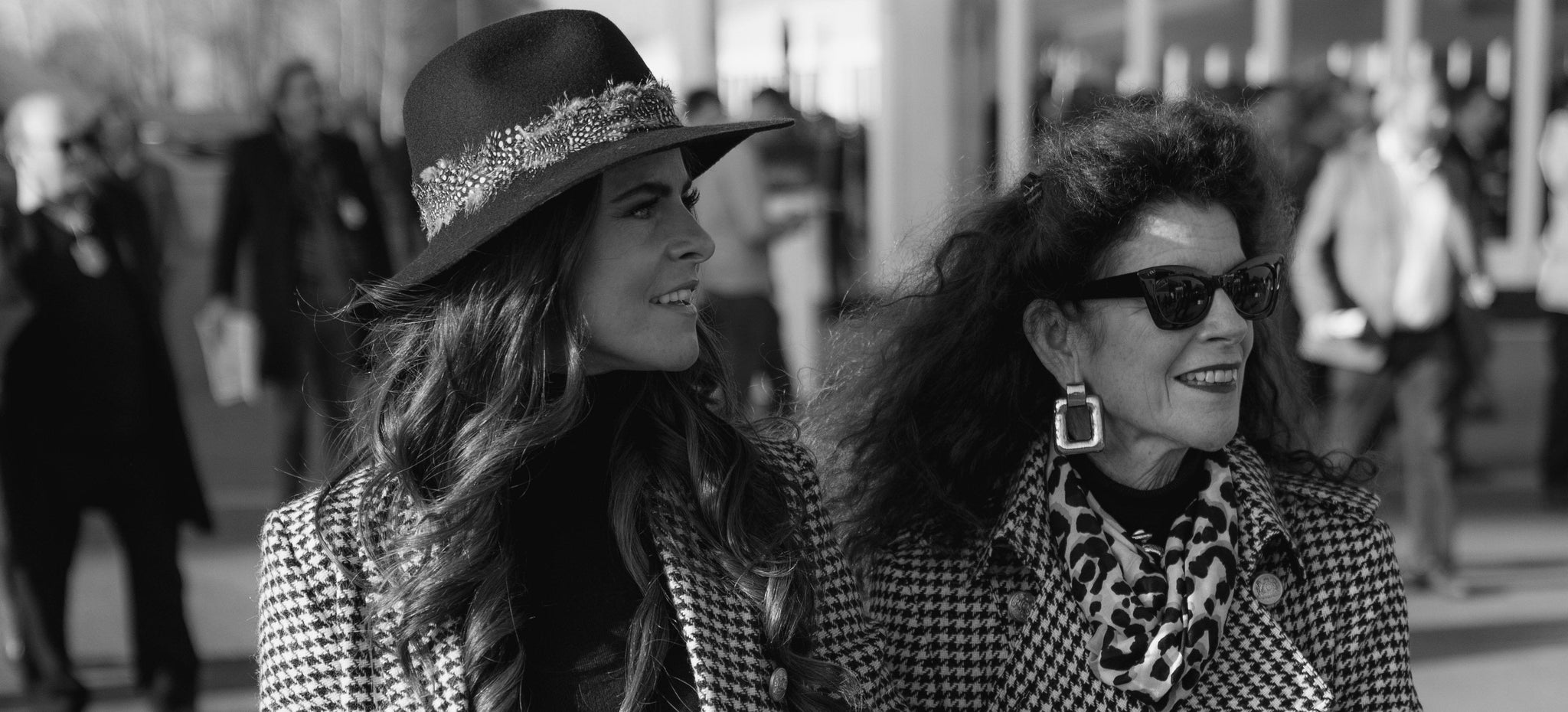 Black and White Image of Jade Holland Cooper and Miranda Holland nee Cooper walking side by side wearing houndstooth trench coats